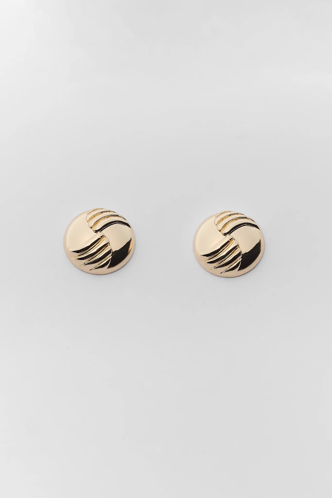 A pair of round gold-toned stud earrings with a textured, wavy black and gold striped pattern, displayed on a clean light gray background.