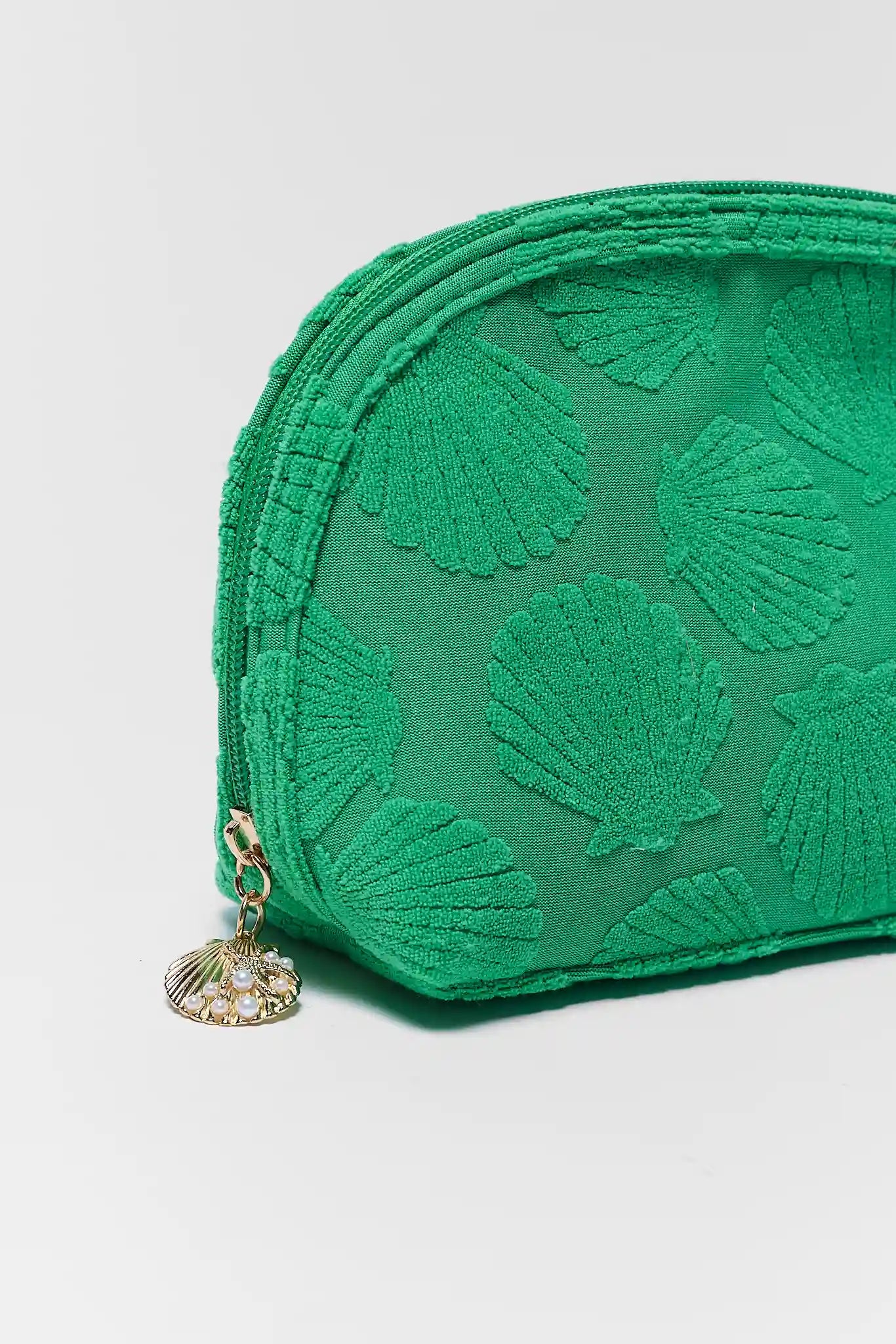 close up Green pouch with shell pattern and gold charm on a light gray background