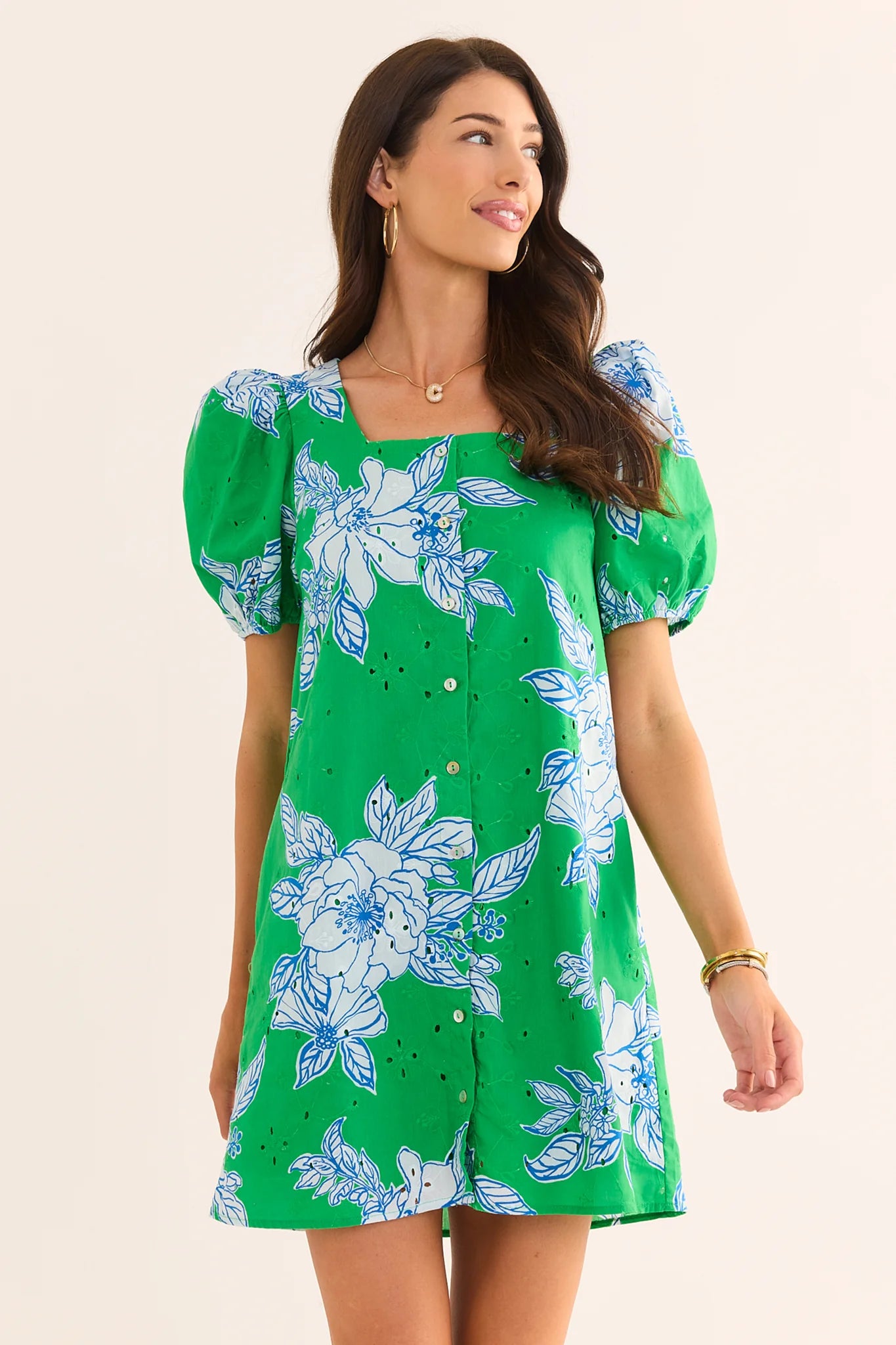 Woman wearing a green floral dress with puff sleeves on a beige background lifestyle