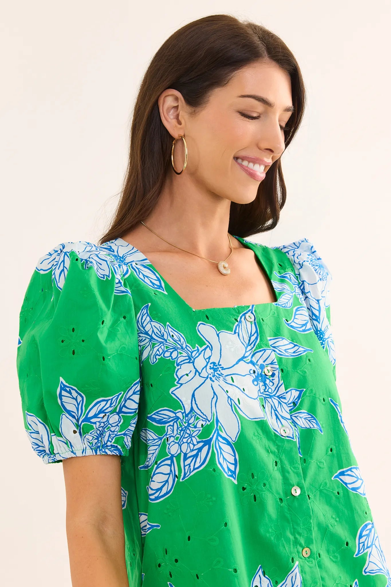 Woman wearing a green floral dress with a plain background lifestyle
