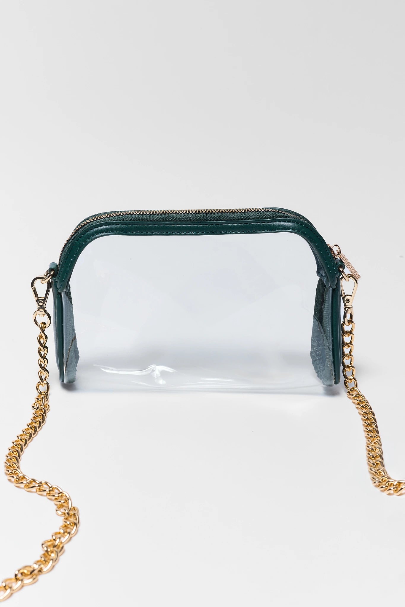 A clear plastic cosmetic pouch with a dark green zipper and trim, featuring a gold-tone chain strap, set against a plain light gray background.