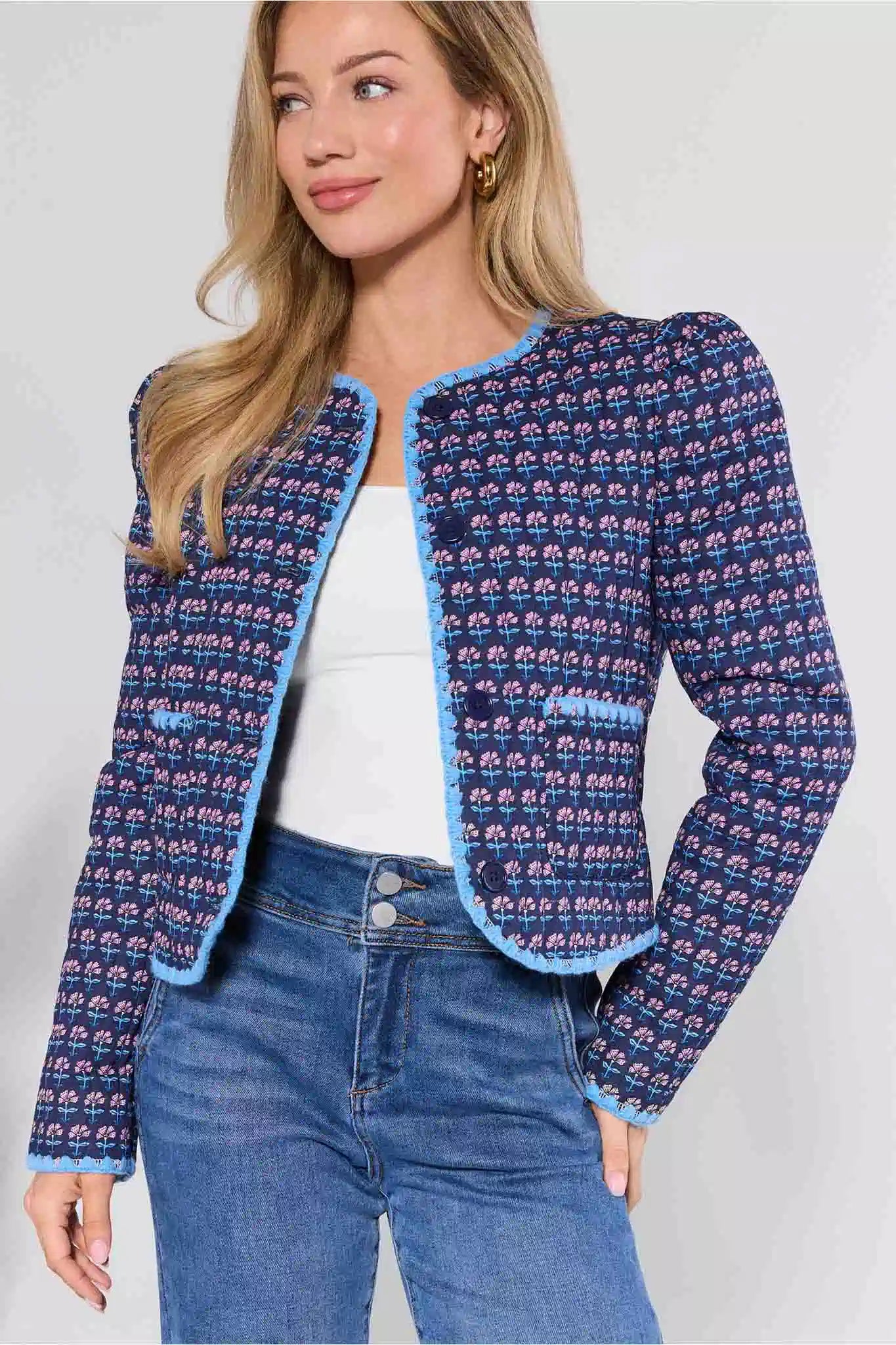 Woman wearing a blue patterned jacket and jeans on a white background