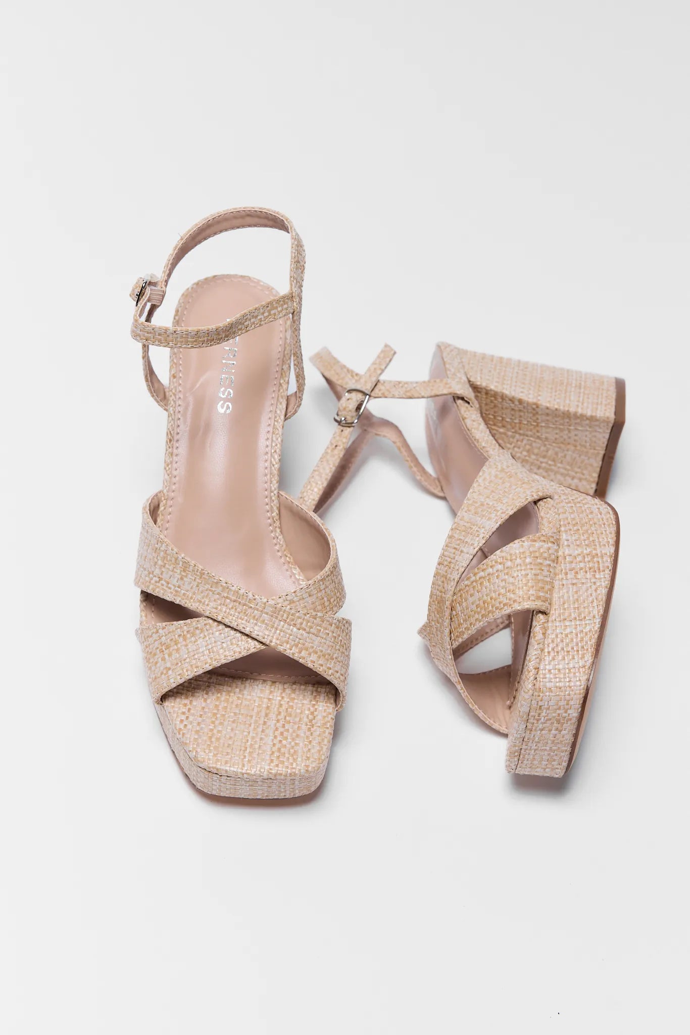 Pair of beige high-heeled sandals on a light gray background
