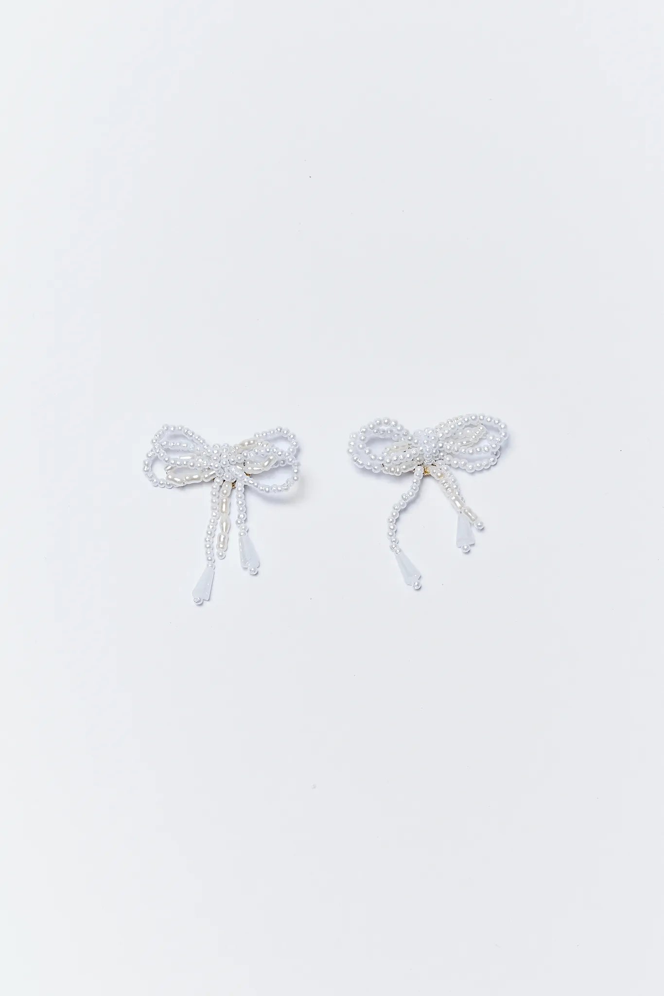 Pair of Gwen Pearl Bow Earrings on a light gray background