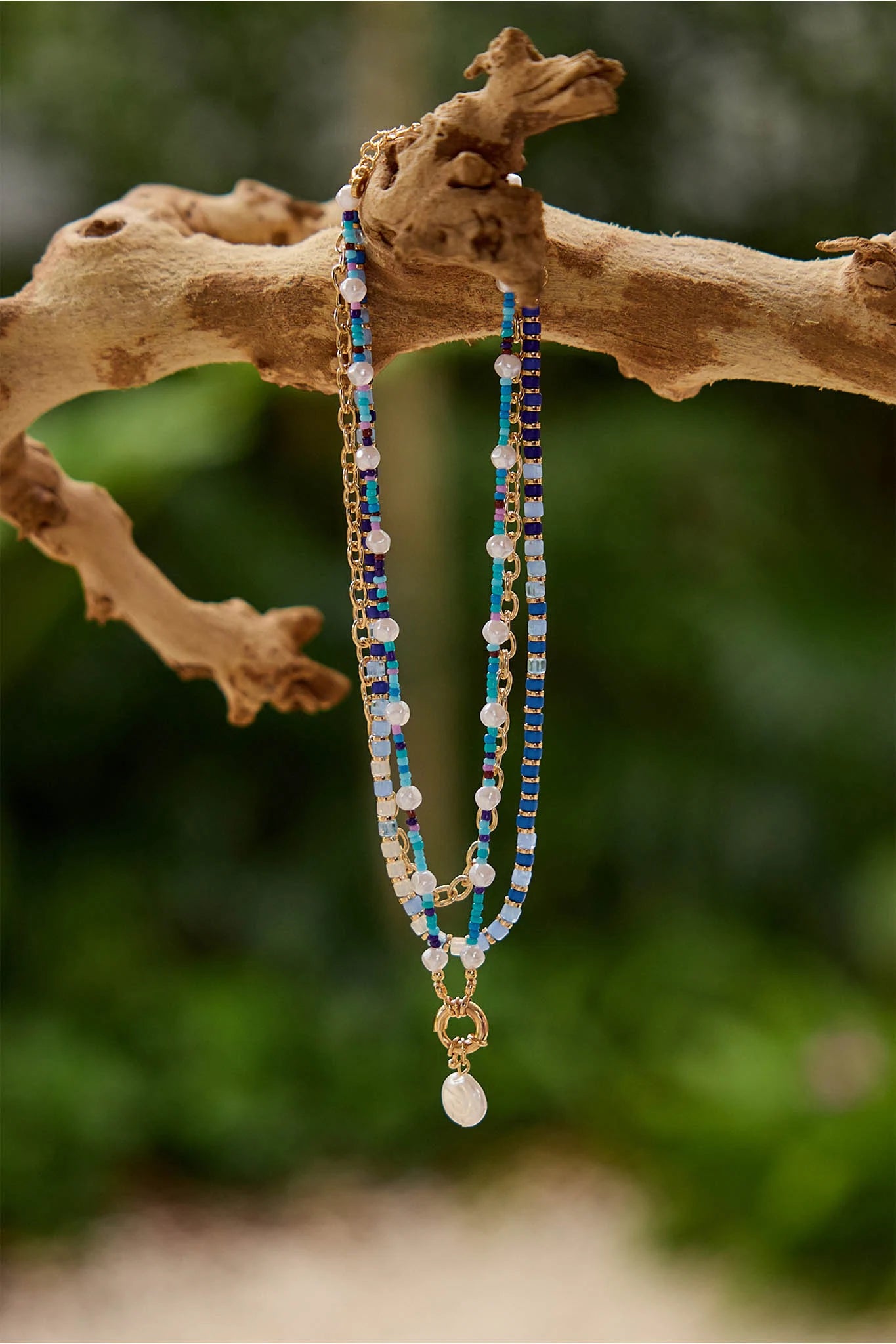 Three beaded necklaces on a branch with a natural background