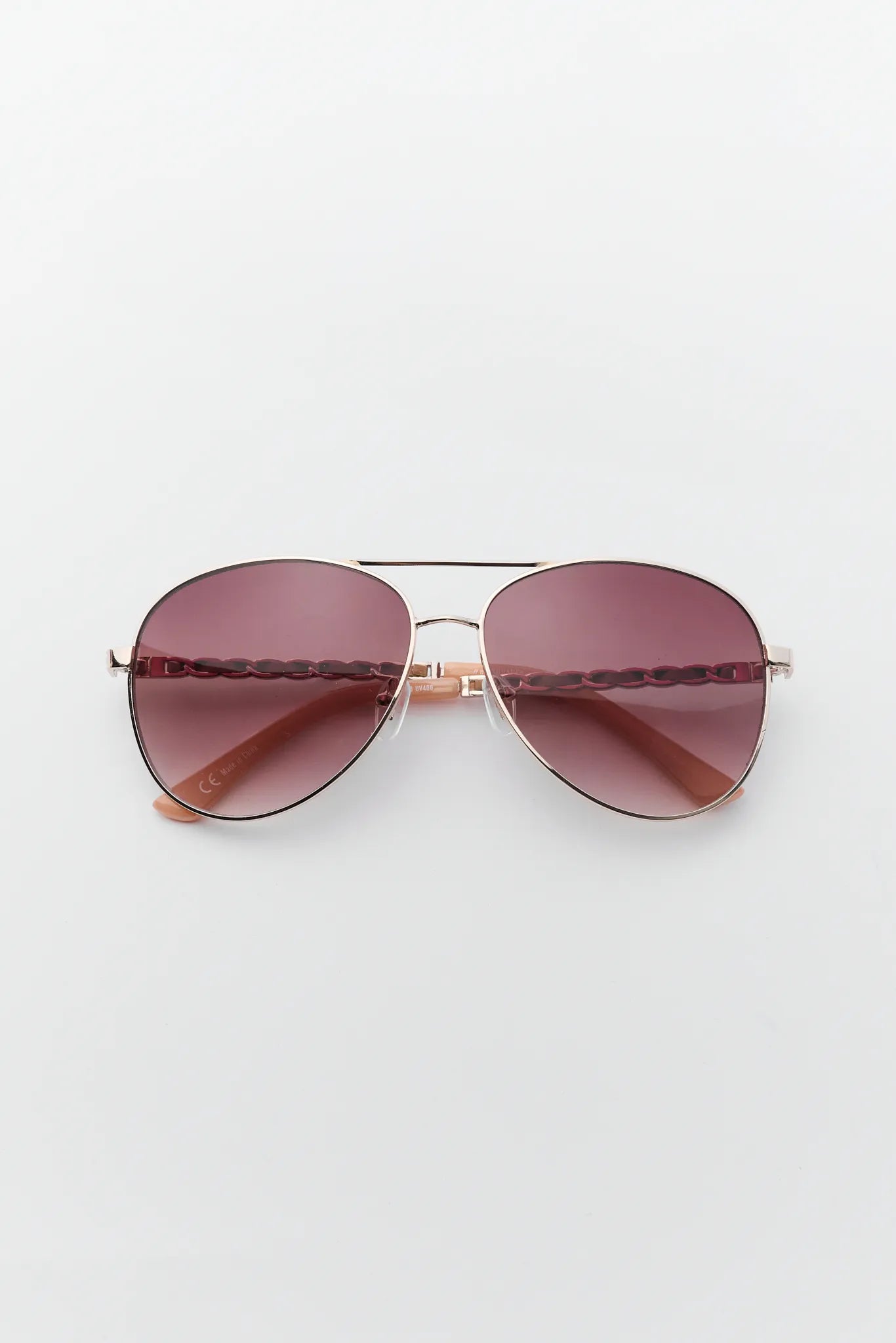 Aviator sunglasses with rose gold frame and red-tinted lenses on a white background
