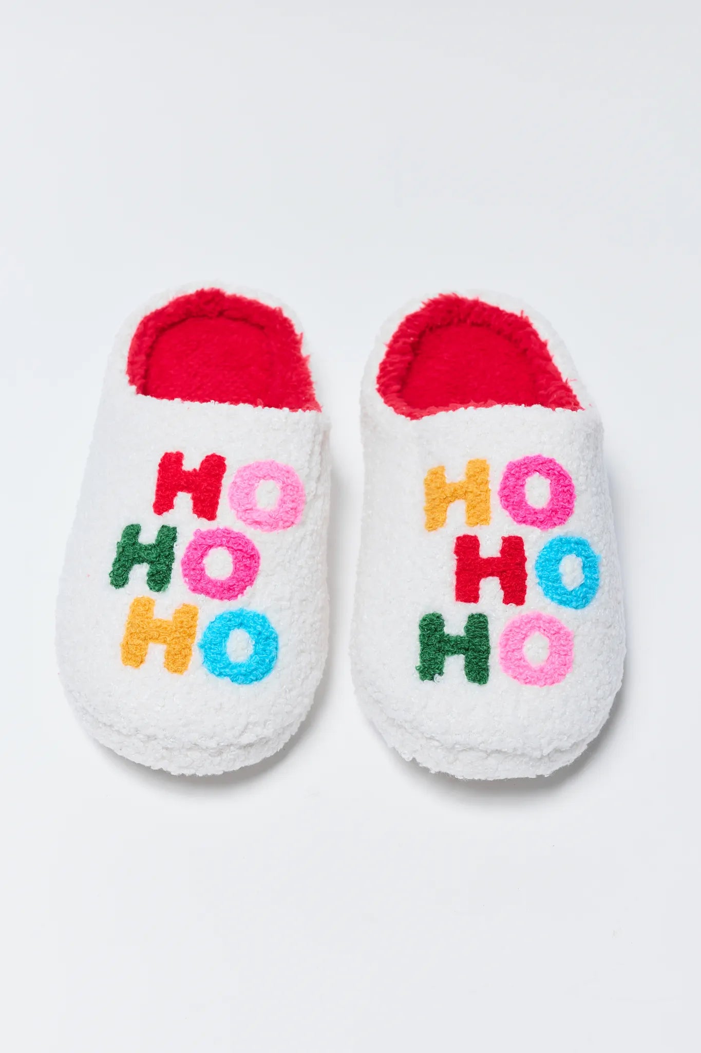 White slippers with red interior and 'HO HO HO' text in colorful letters on a light gray background