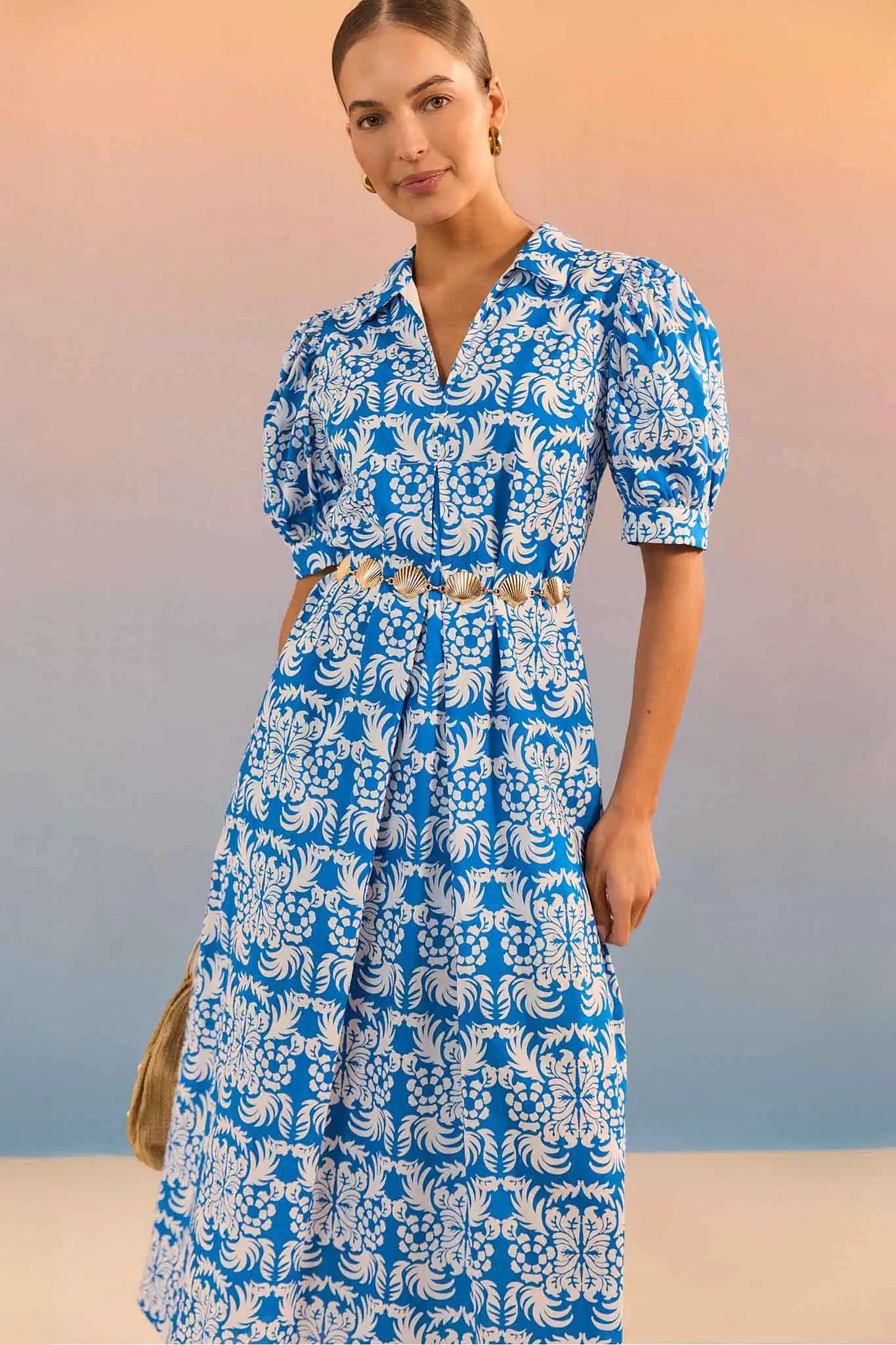 Woman wearing a blue and white floral dress against a gradient background