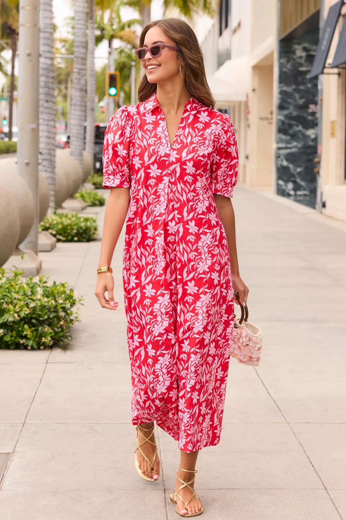Woman wearing a red floral dress on a city street. lifestyle