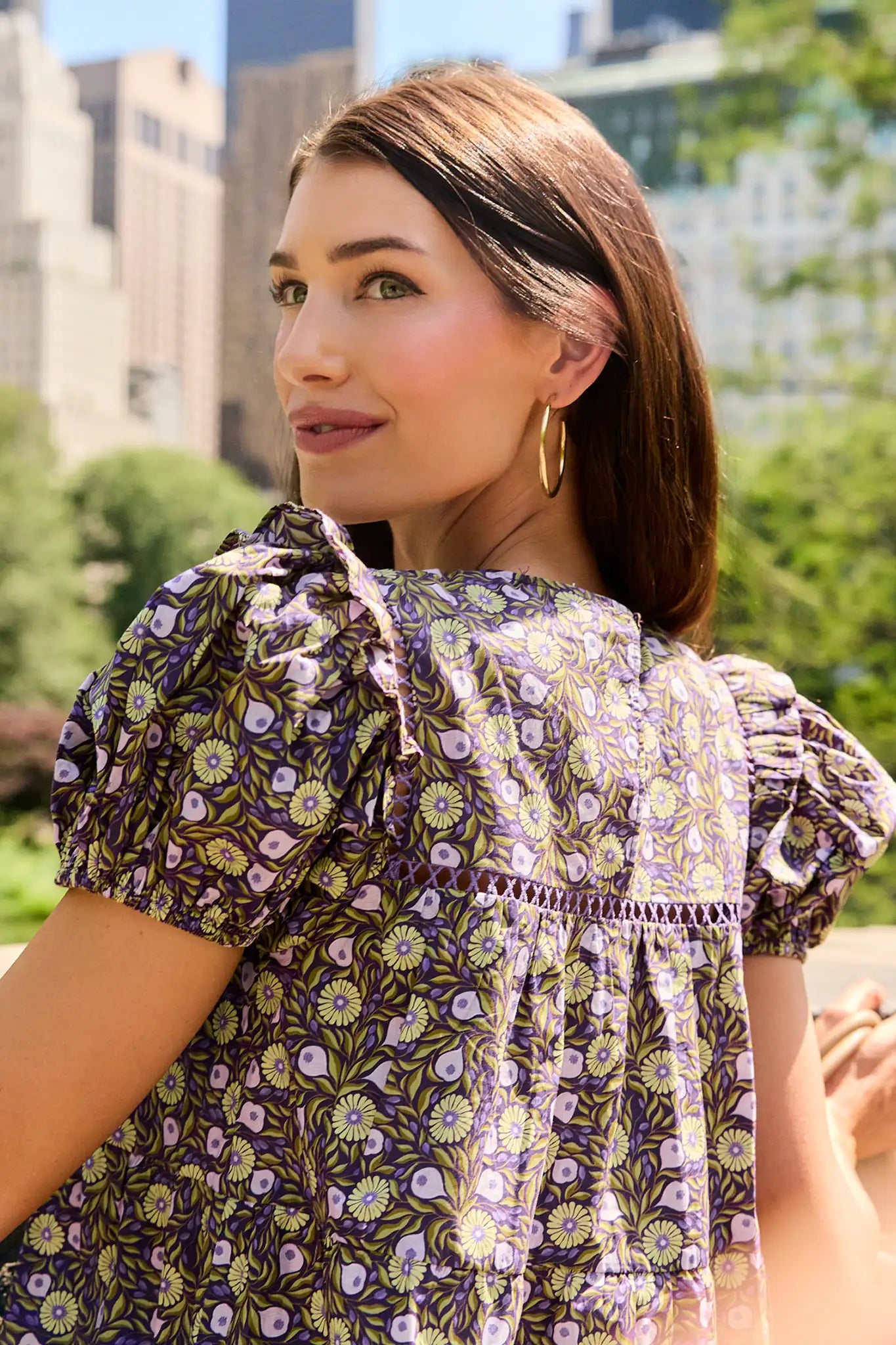 Woman standing in the city wearing a floral blouse with puff sleeves 