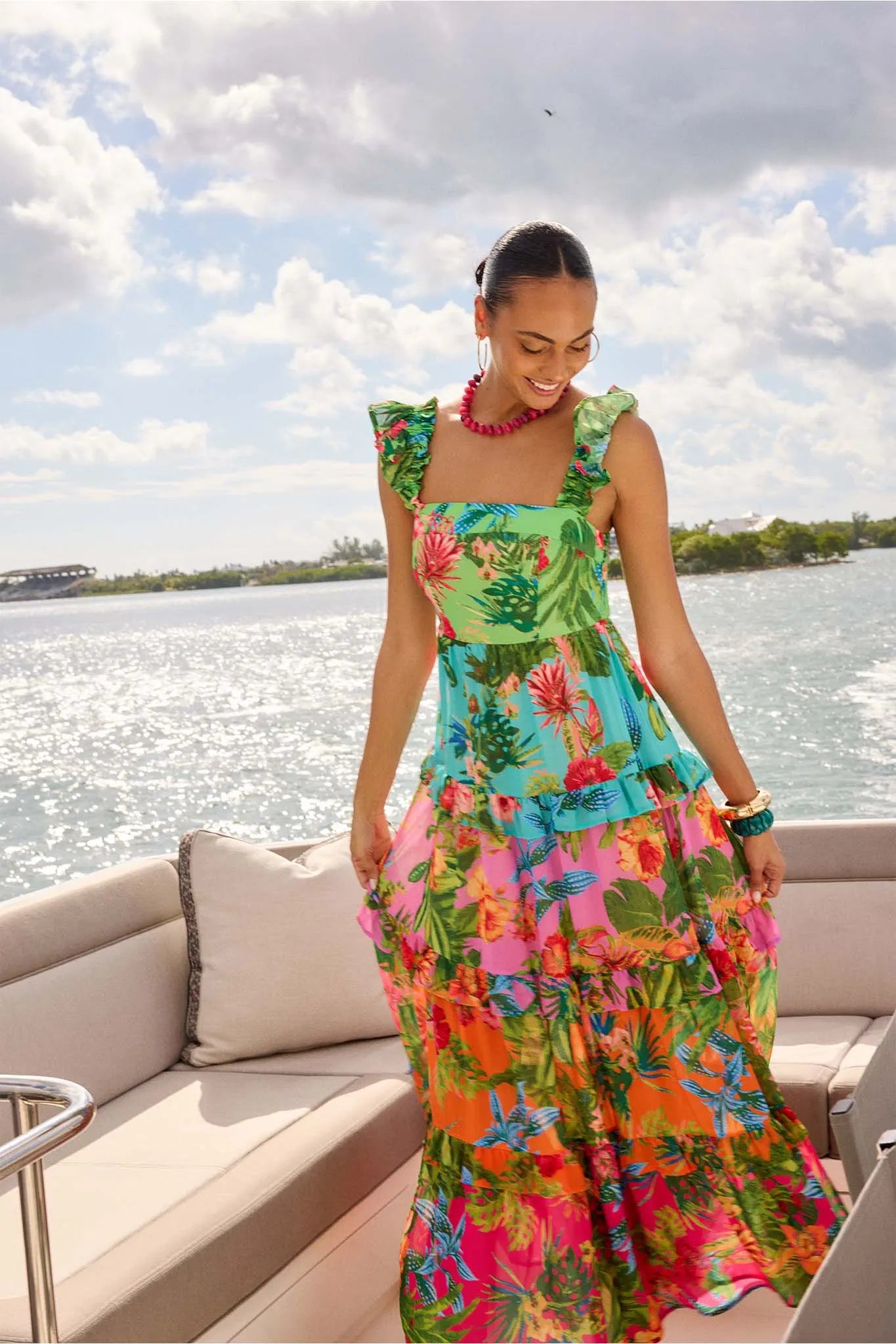 Woman in a colorful floral dress on a boat with water and sky in the background