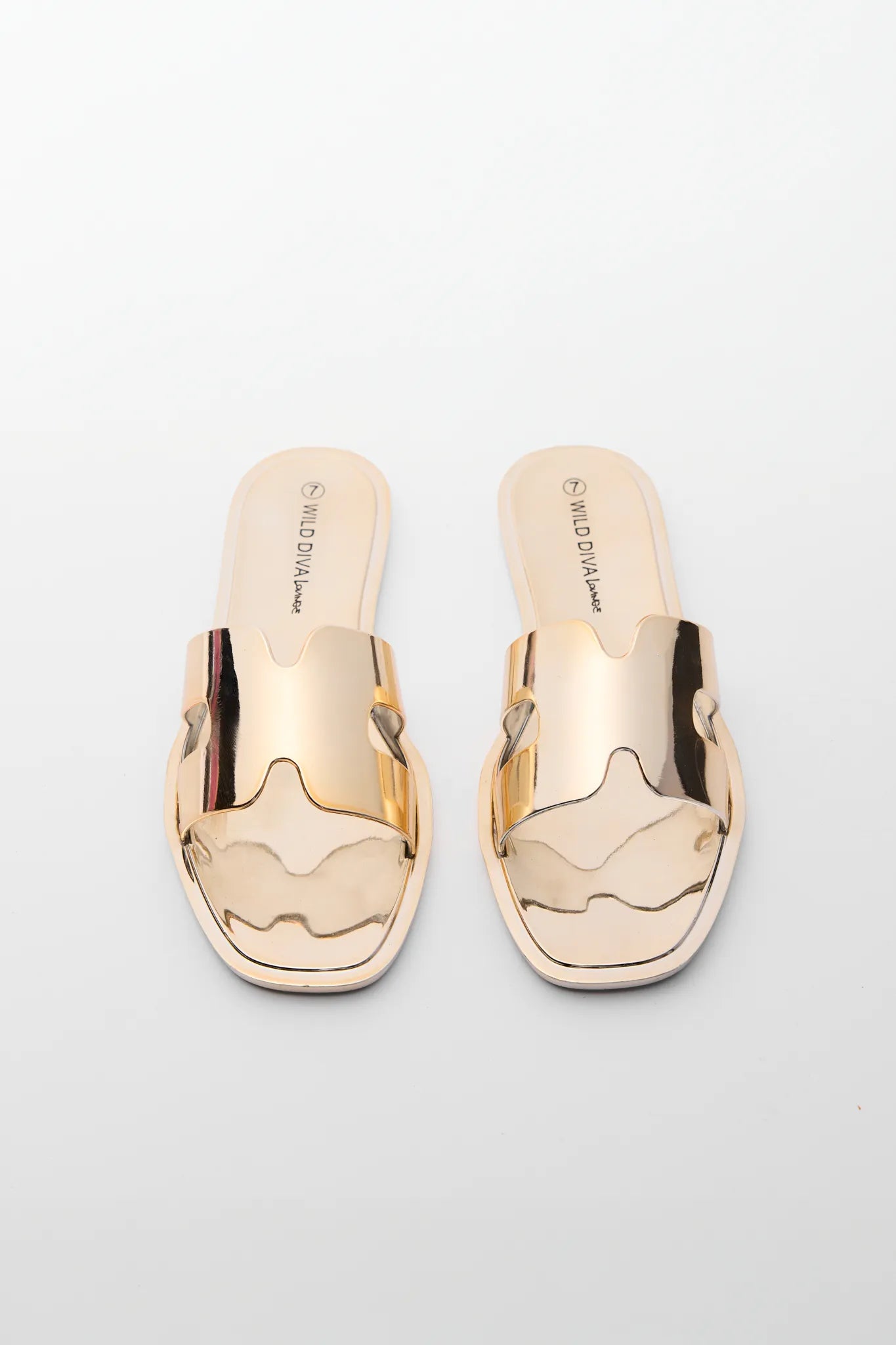 Pair of metallic gold sandals on a light gray background