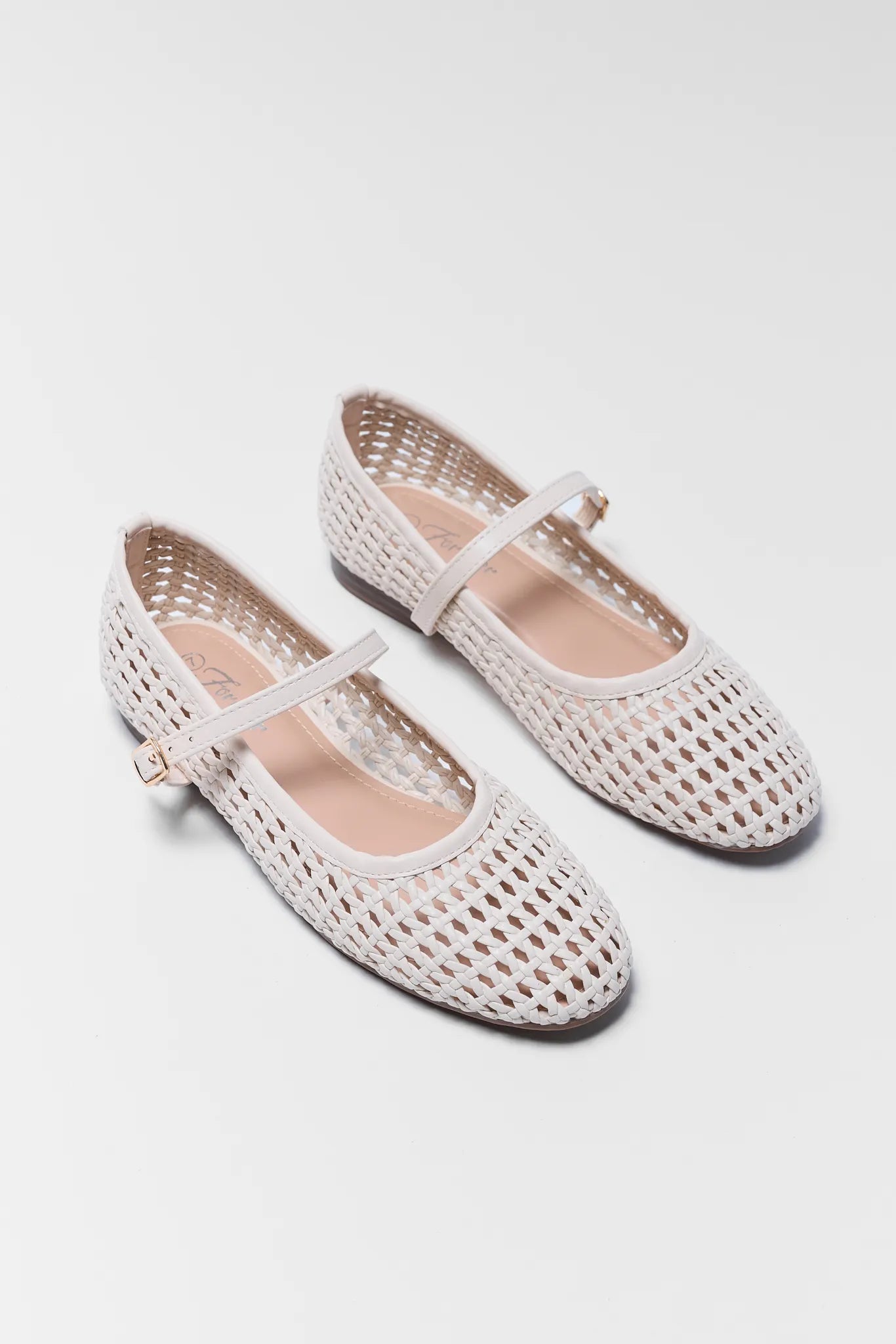 Pair of white woven shoes with thin straps on a light gray background