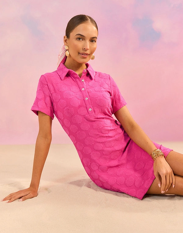 Woman wearing a pink dress sitting on a beach with a pastel sky background