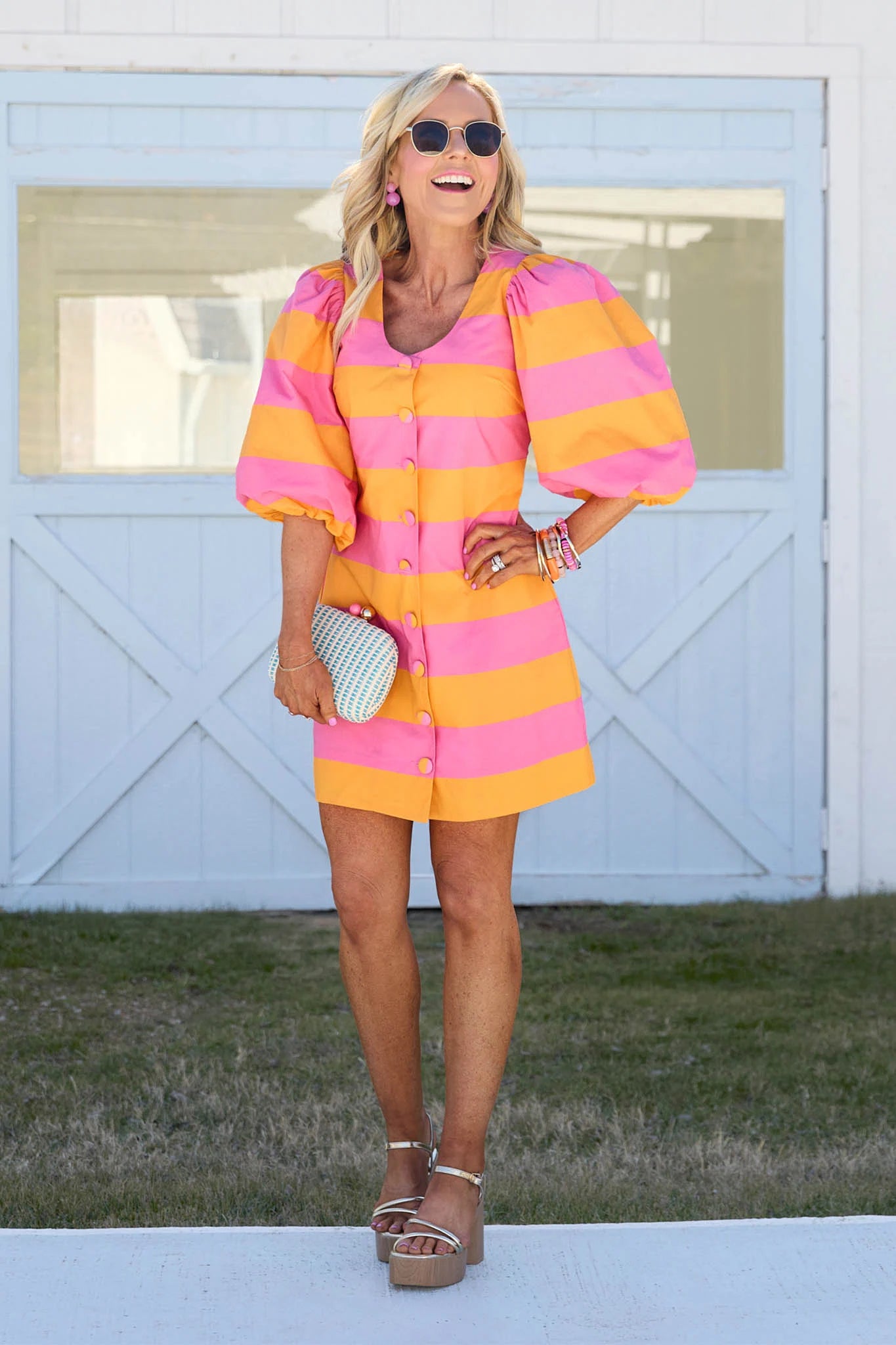 Woman wearing a colorful striped dress standing in front of a white wooden door.
