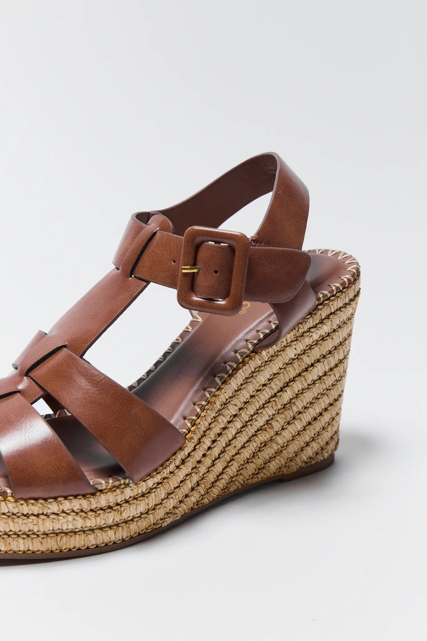 Brown wedge sandal with woven sole on a light gray background