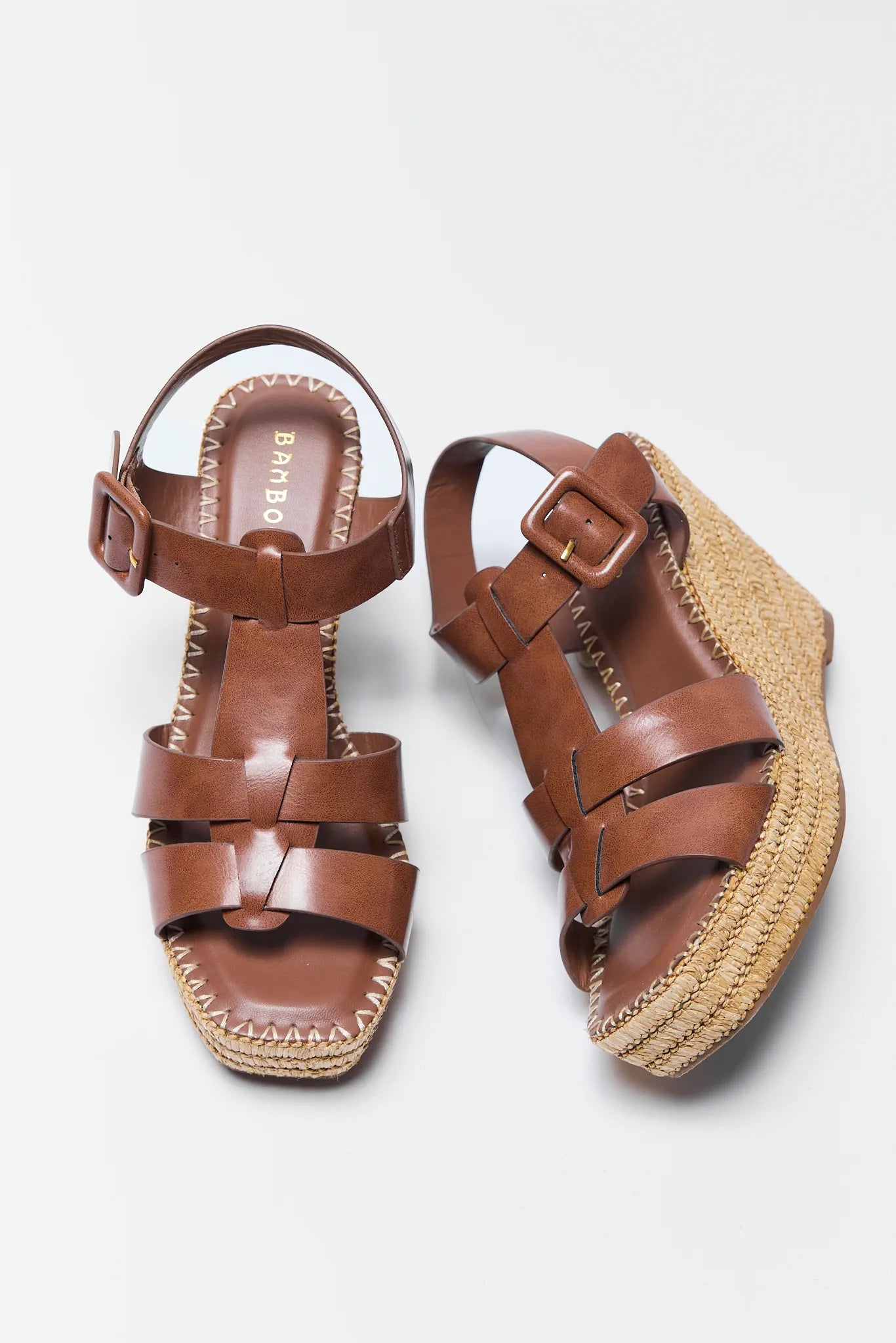 Pair of brown sandals with woven sole on a white background