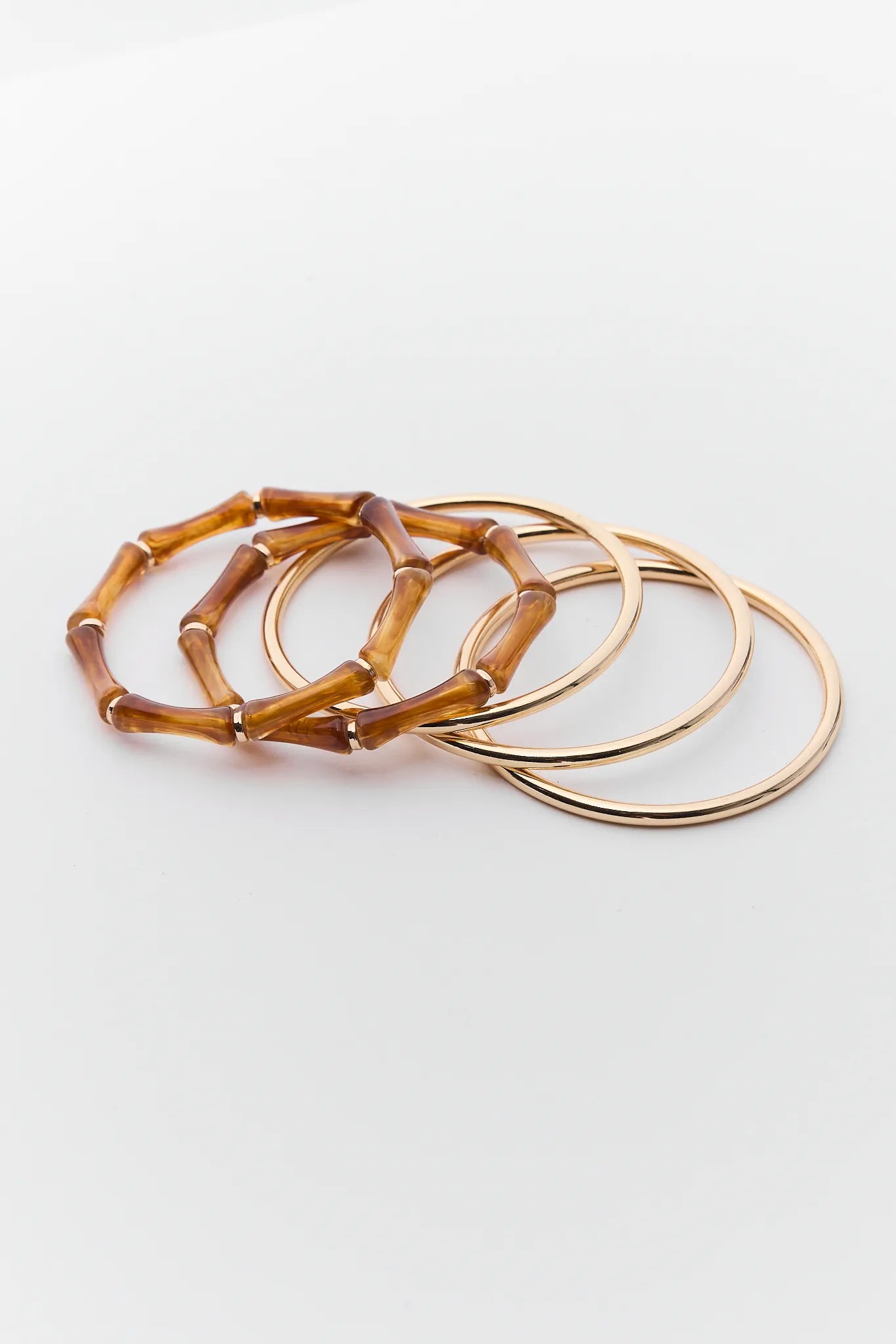 Set of tortoiseshell and gold bangles on a white background