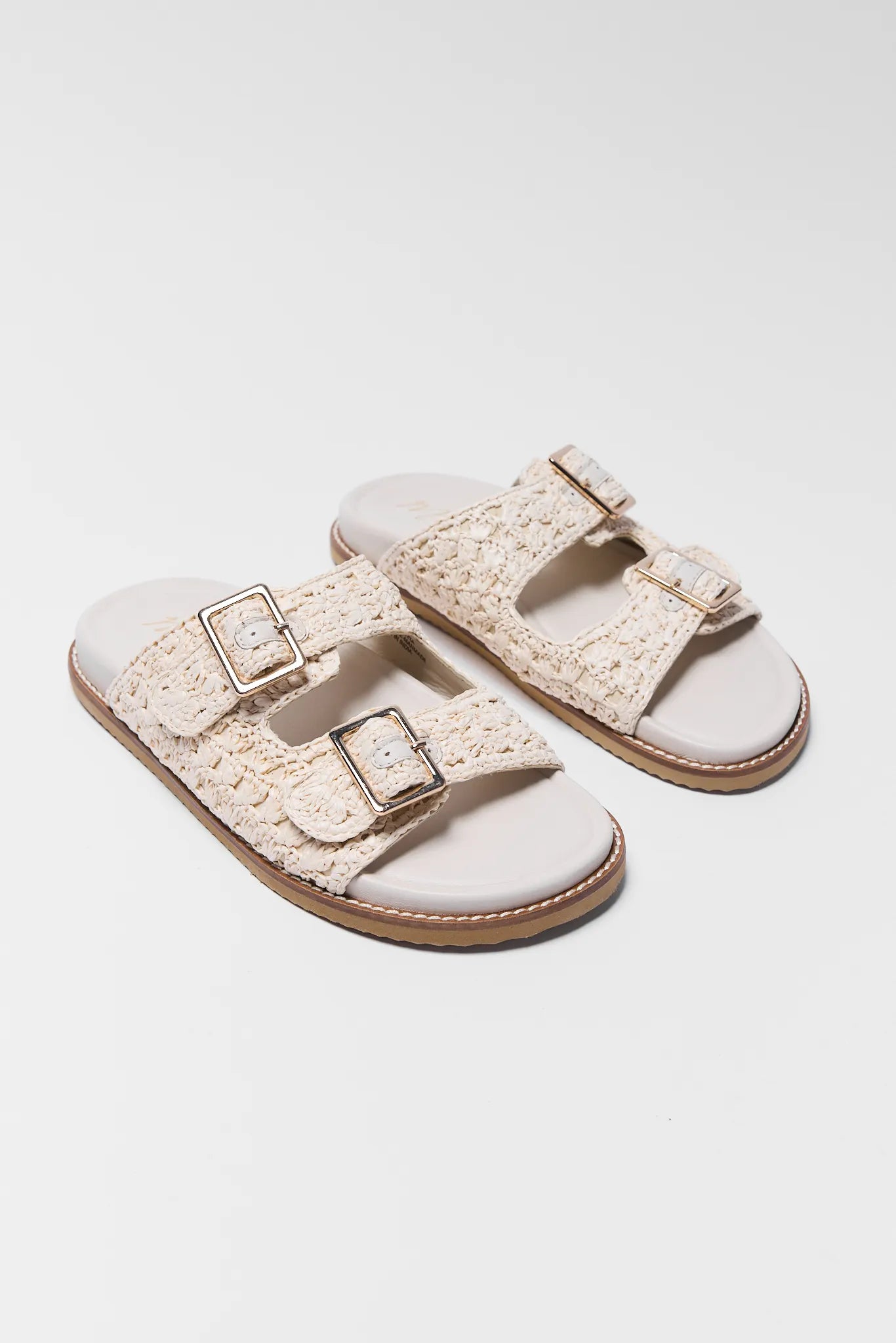 white sandals with double straps on a light gray background