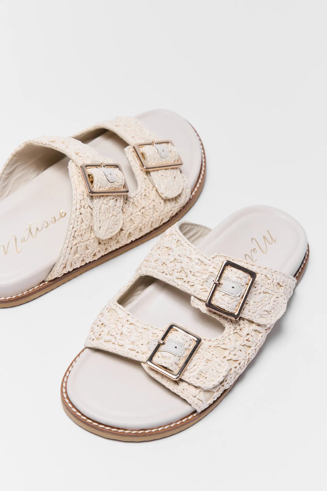 Pair of beige sandals with buckles on a white background