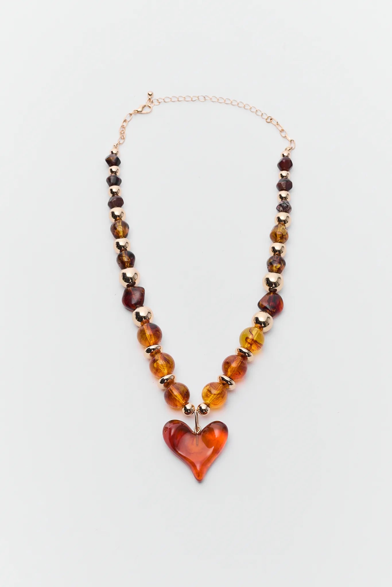 Necklace with heart-shaped amber pendant on a light gray background