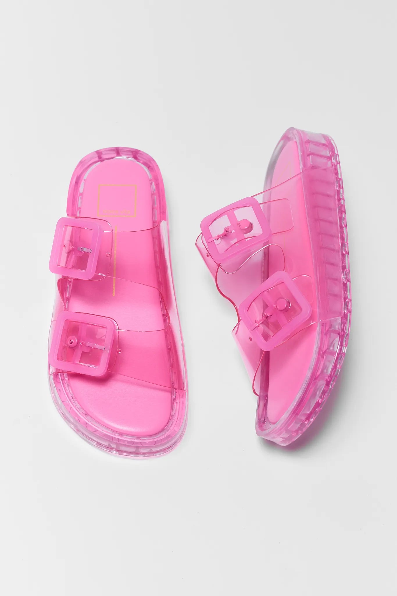 Pair of pink sandals with clear soles on a light gray background