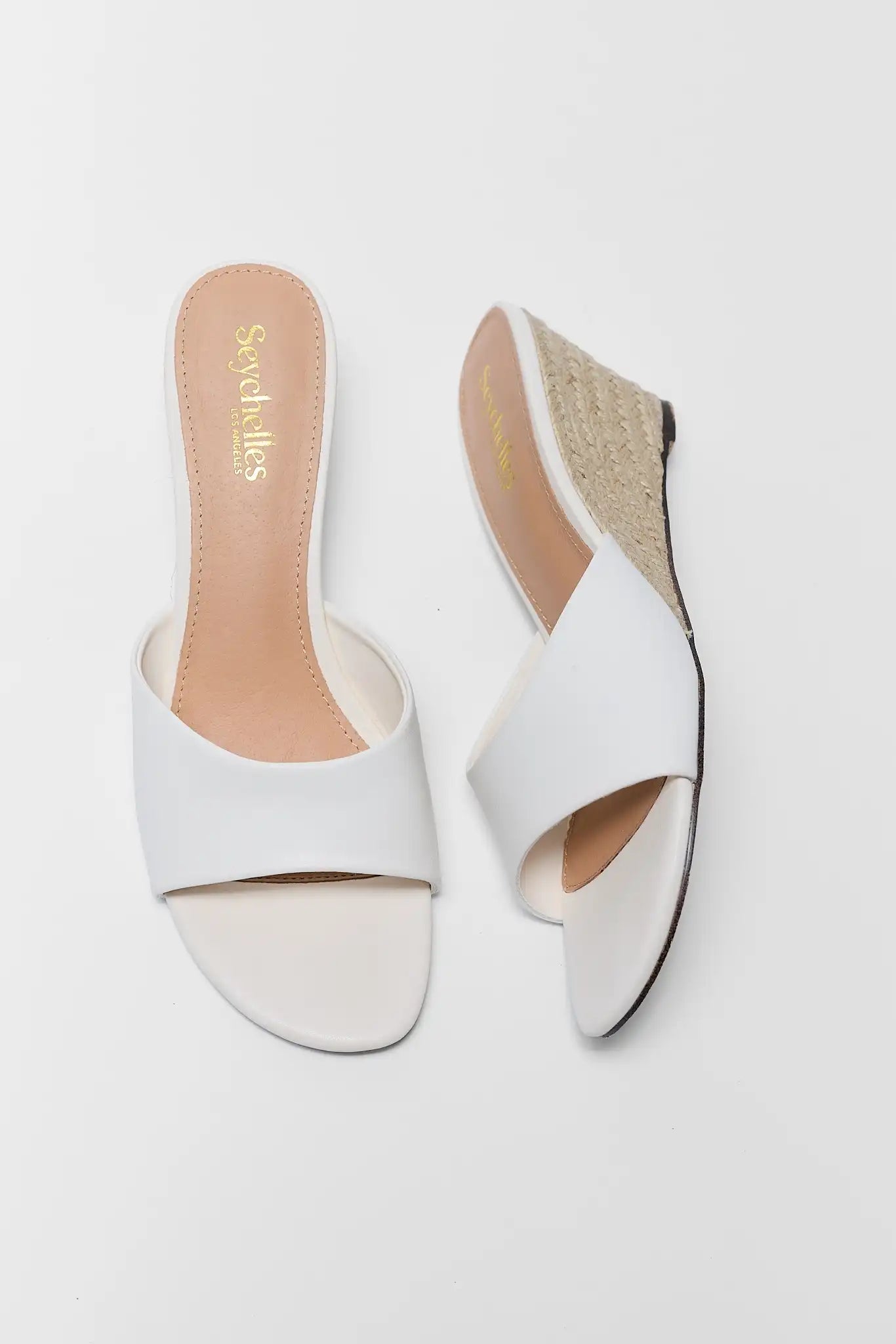 White open-toe shoes with beige soles on a white background