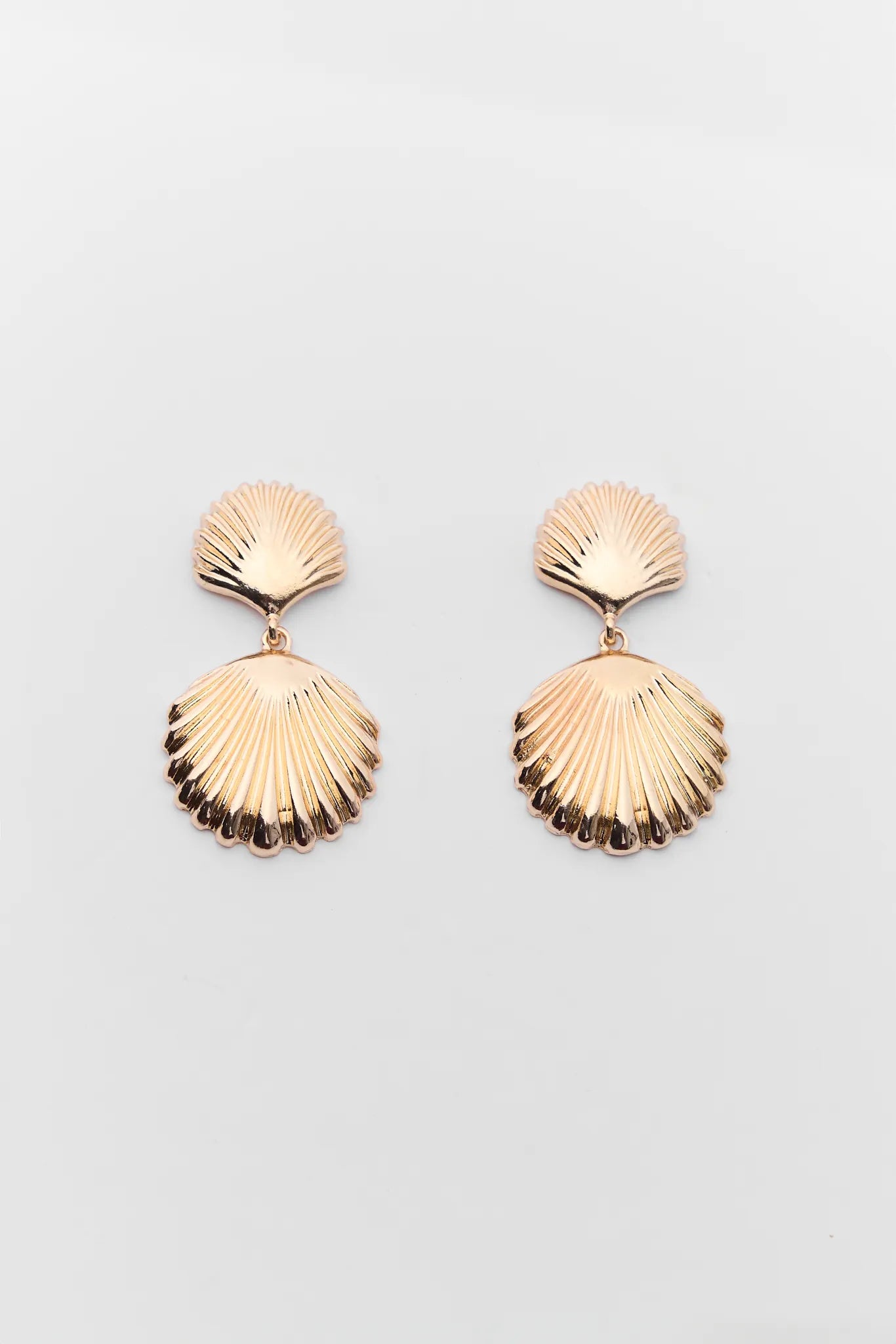 Pair of gold shell-shaped earrings on a light gray background