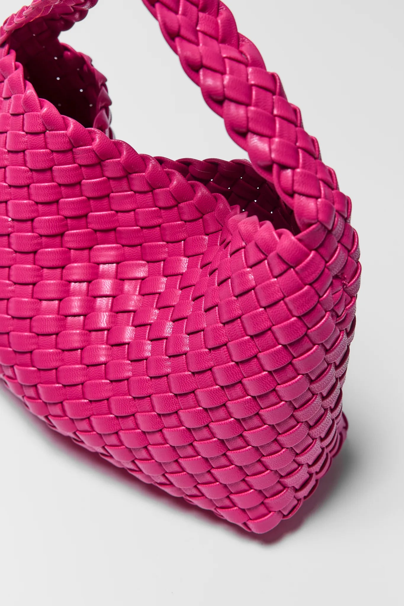 Close-up of a pink woven handbag on a light gray background
