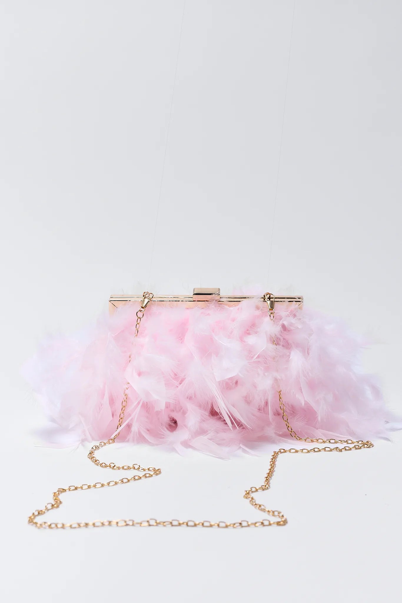 Pink feathered handbag with gold chain on a white background