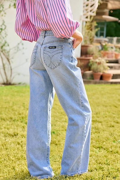 Person wearing light blue jeans and a pink striped shirt outdoors on grass