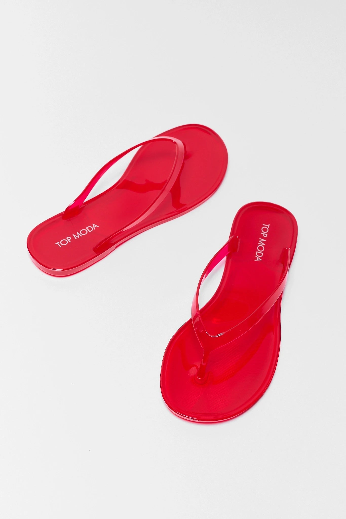 Red flip-flops with 'Top Moda' branding on a white background