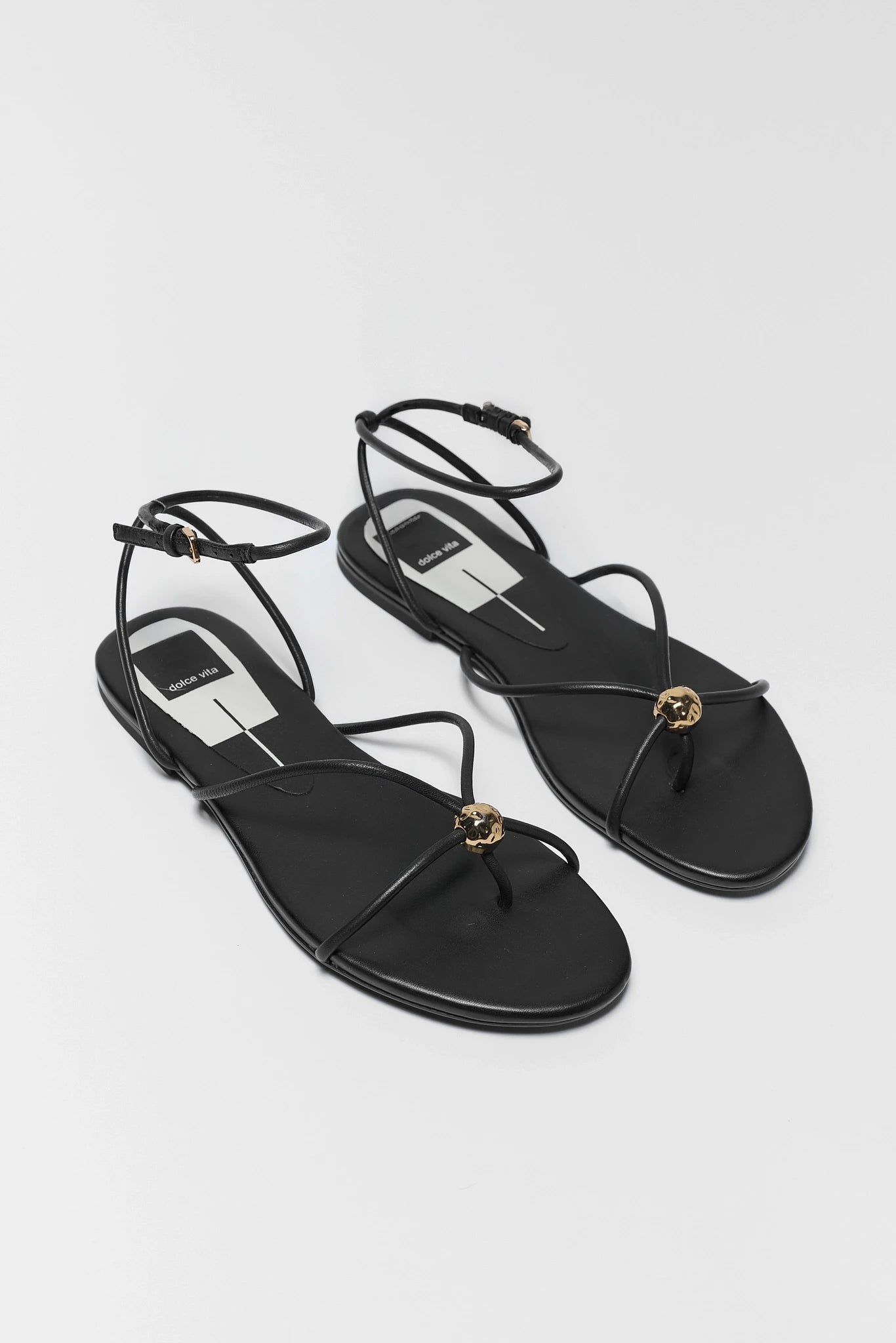 two black sandals with thin straps on a light background
