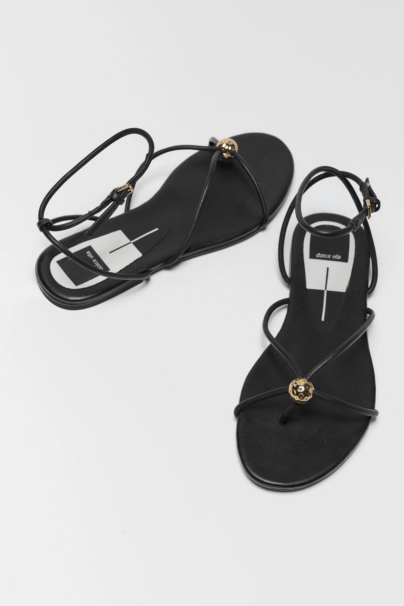 Black sandals with gold accents on a white background