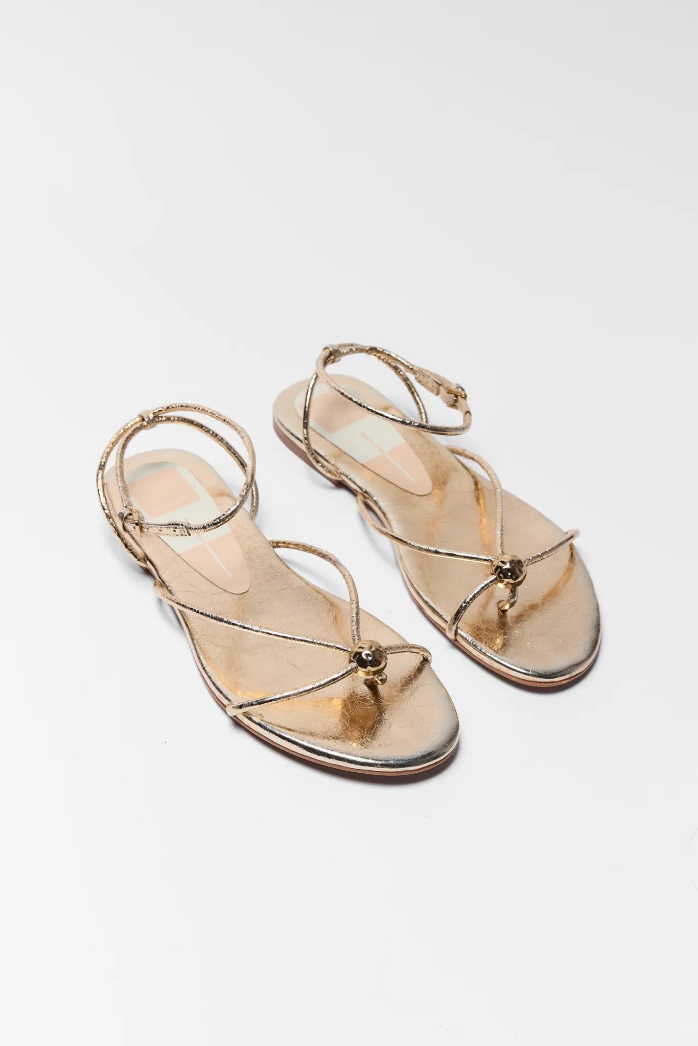 Pair of gold sandals on a light gray background