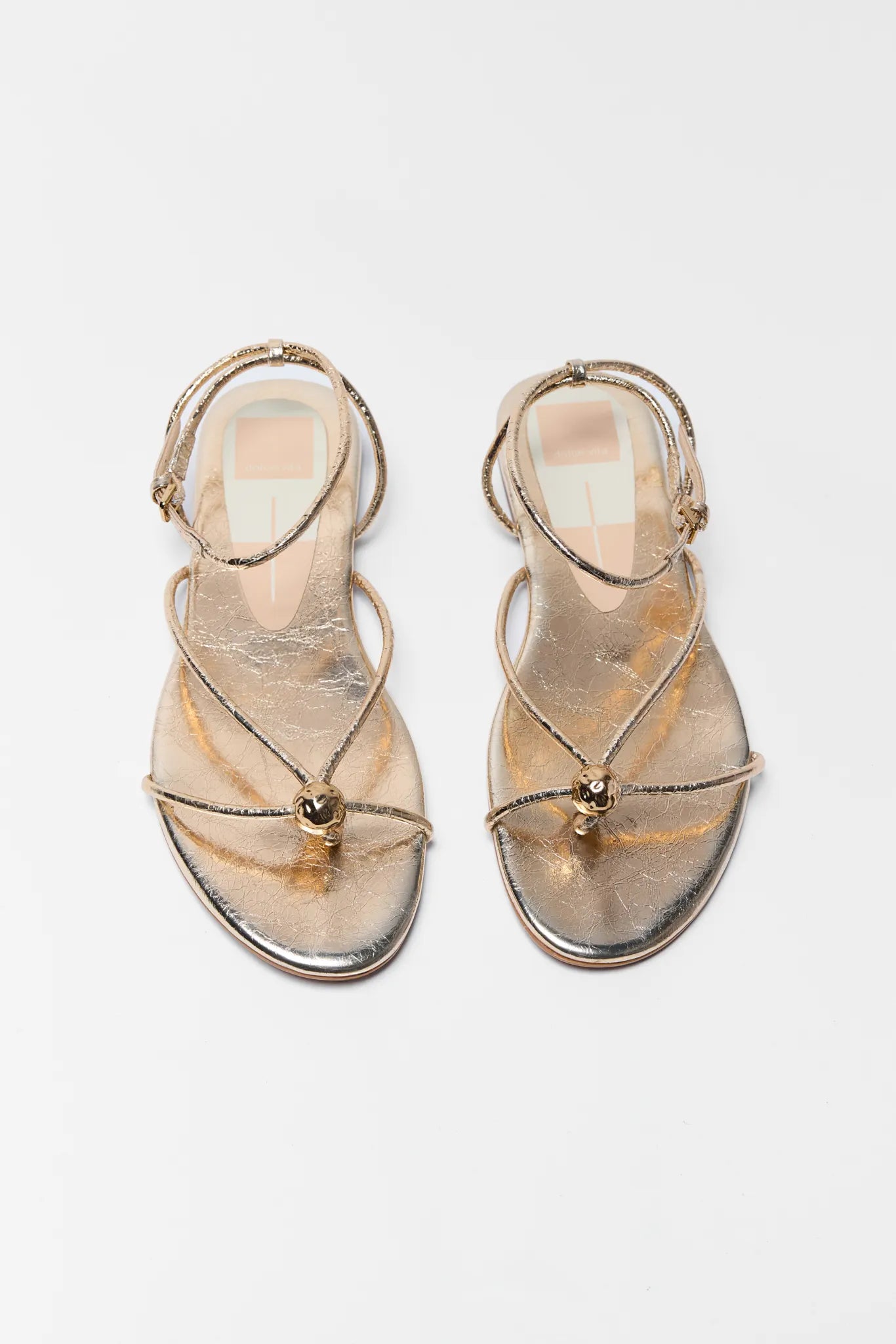 Pair of gold strap sandals on a white background