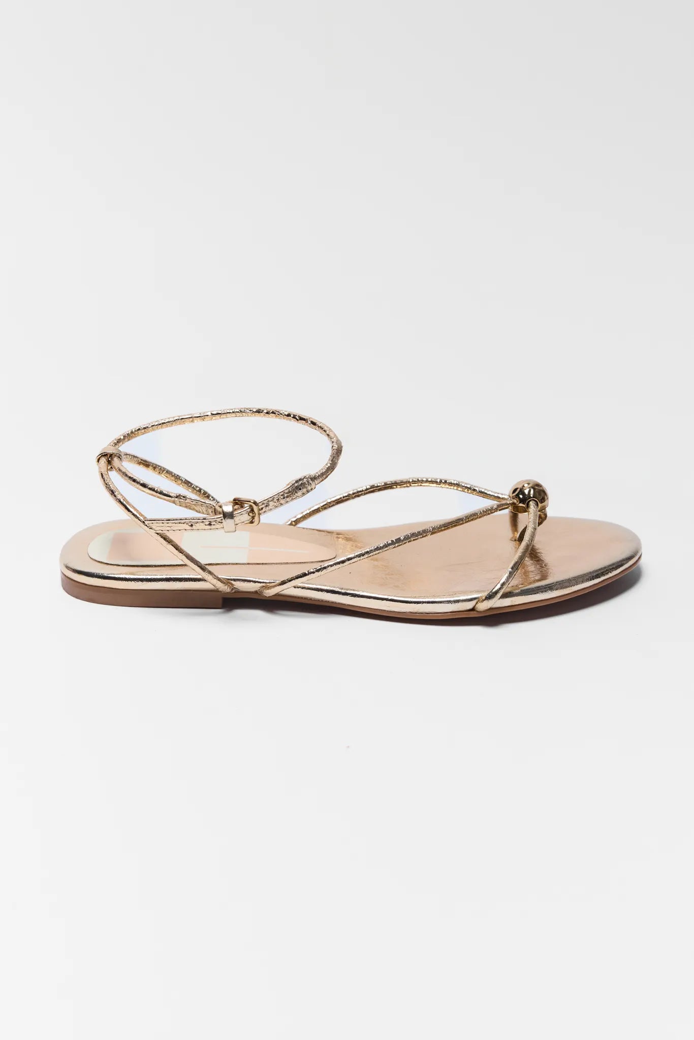 Gold sandal with thin straps on a white background