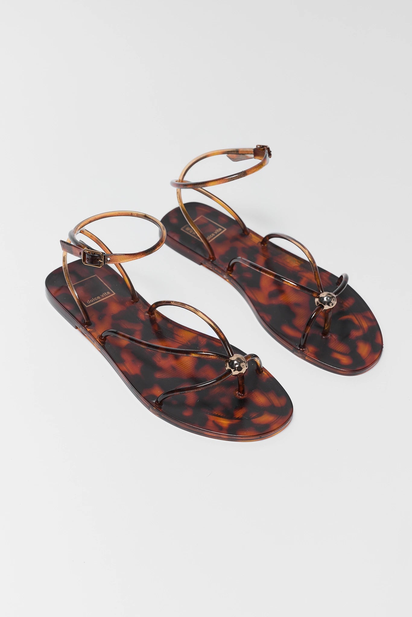 two Tortoiseshell sandals on a light gray background