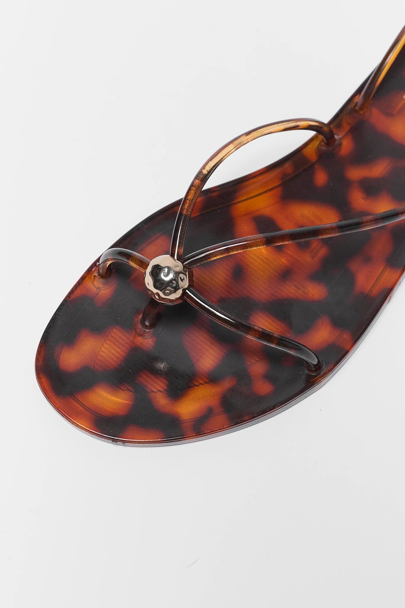 close up Tortoiseshell sandal with a decorative thong on a light gray background