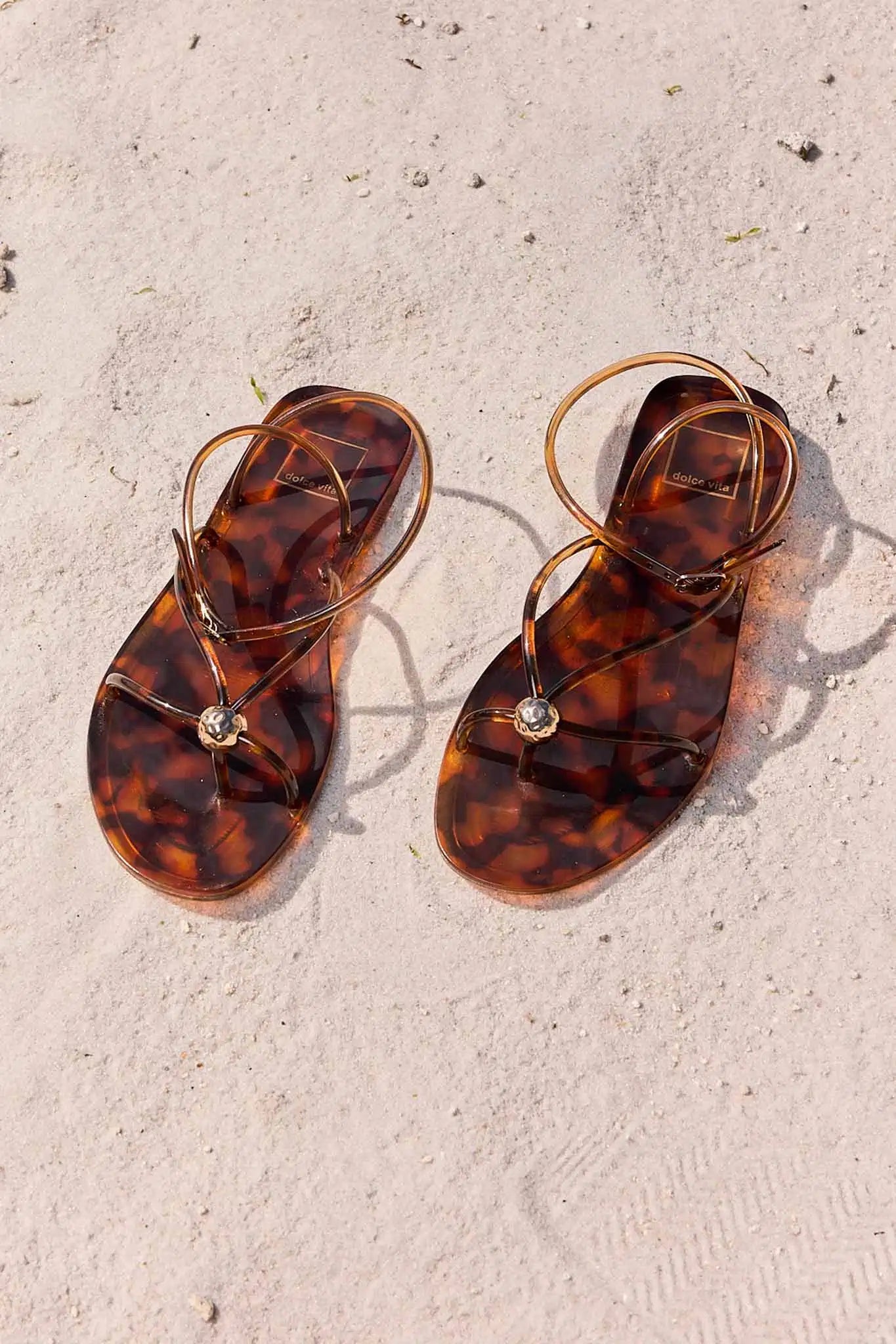 Tortoiseshell sandals on a sandy surface