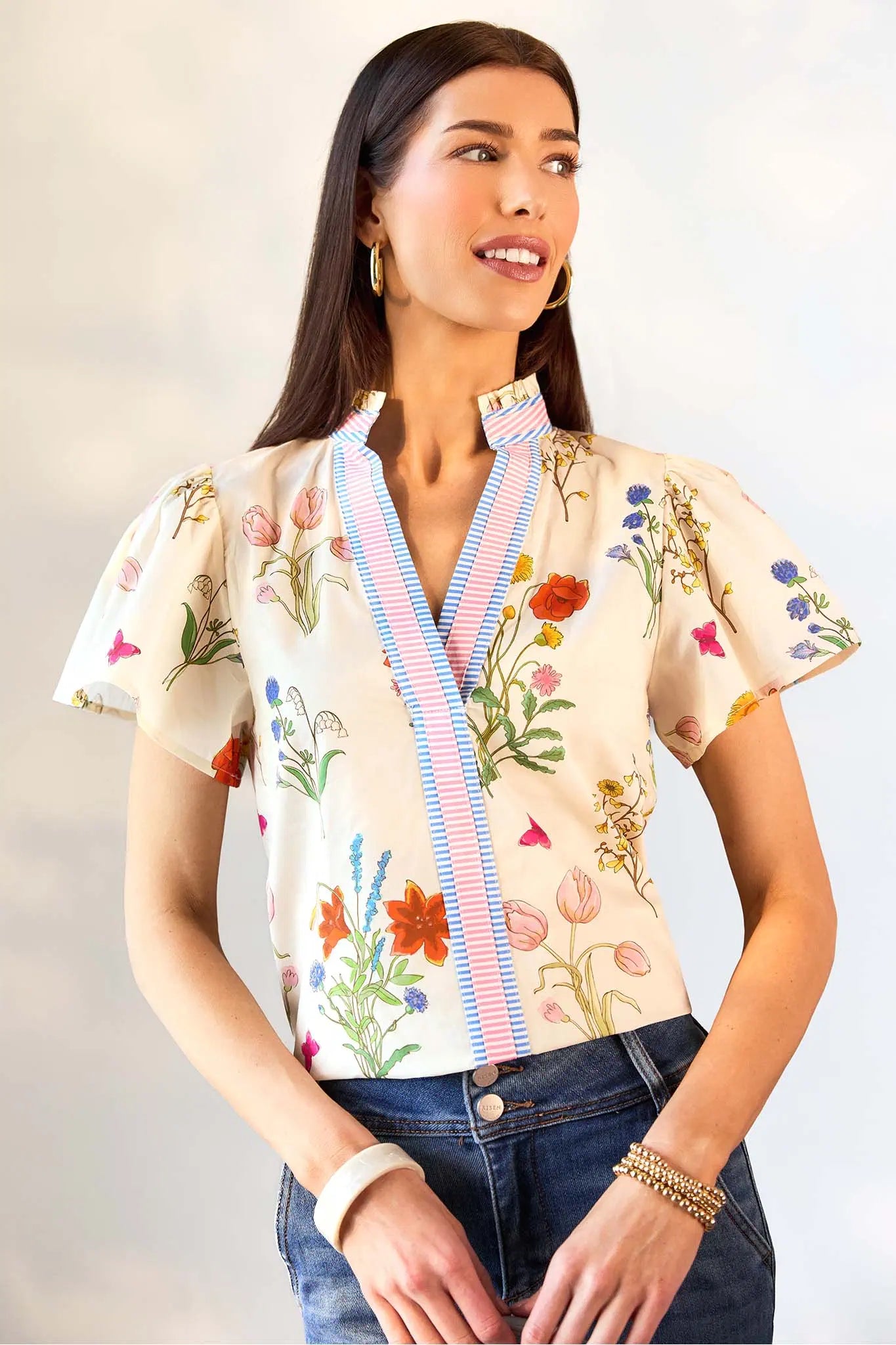 Woman wearing a floral blouse with a striped yoke against a plain background