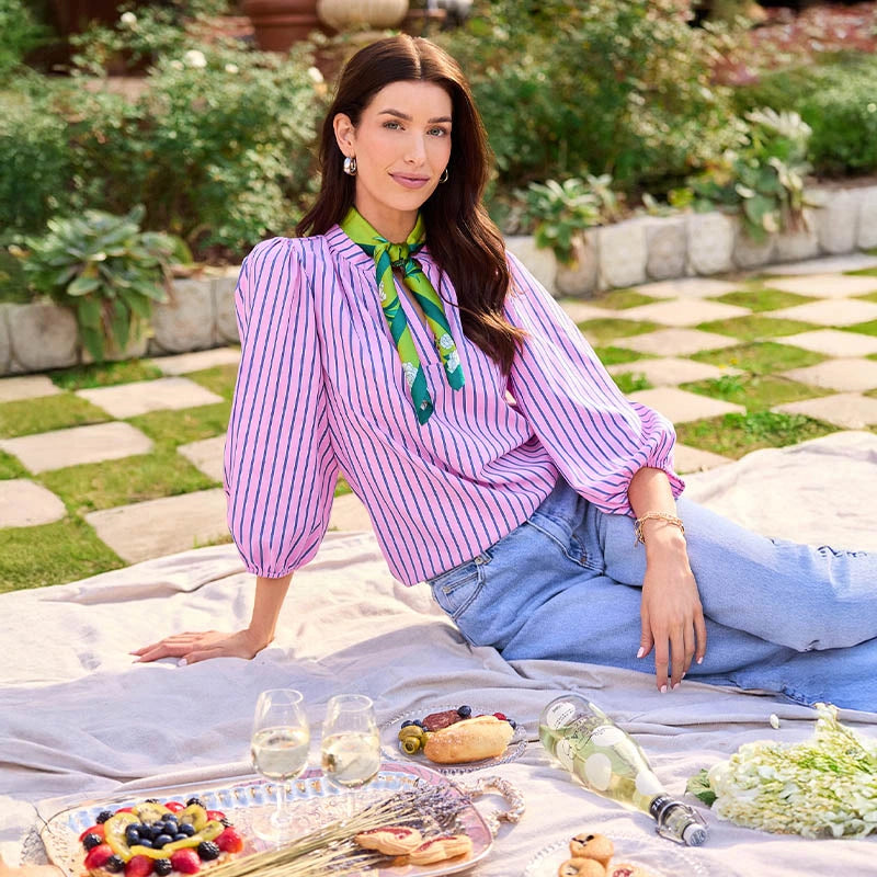 Woman sitting on a blanket with a picnic spread in a garden