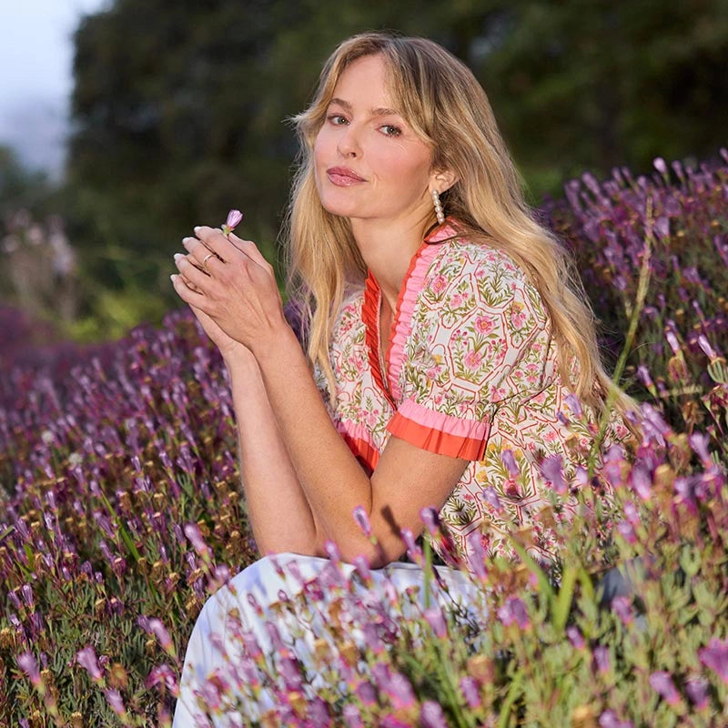 Woman in a patterned dress sitting among lavender flowers