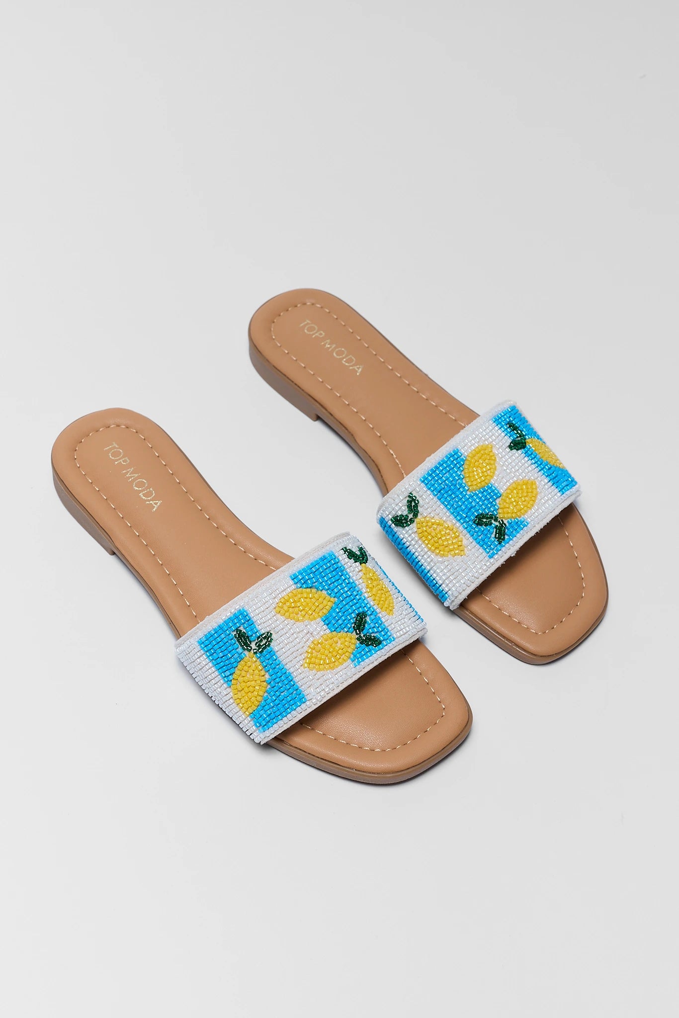 Pair of sandals with lemon design on a light gray background two
