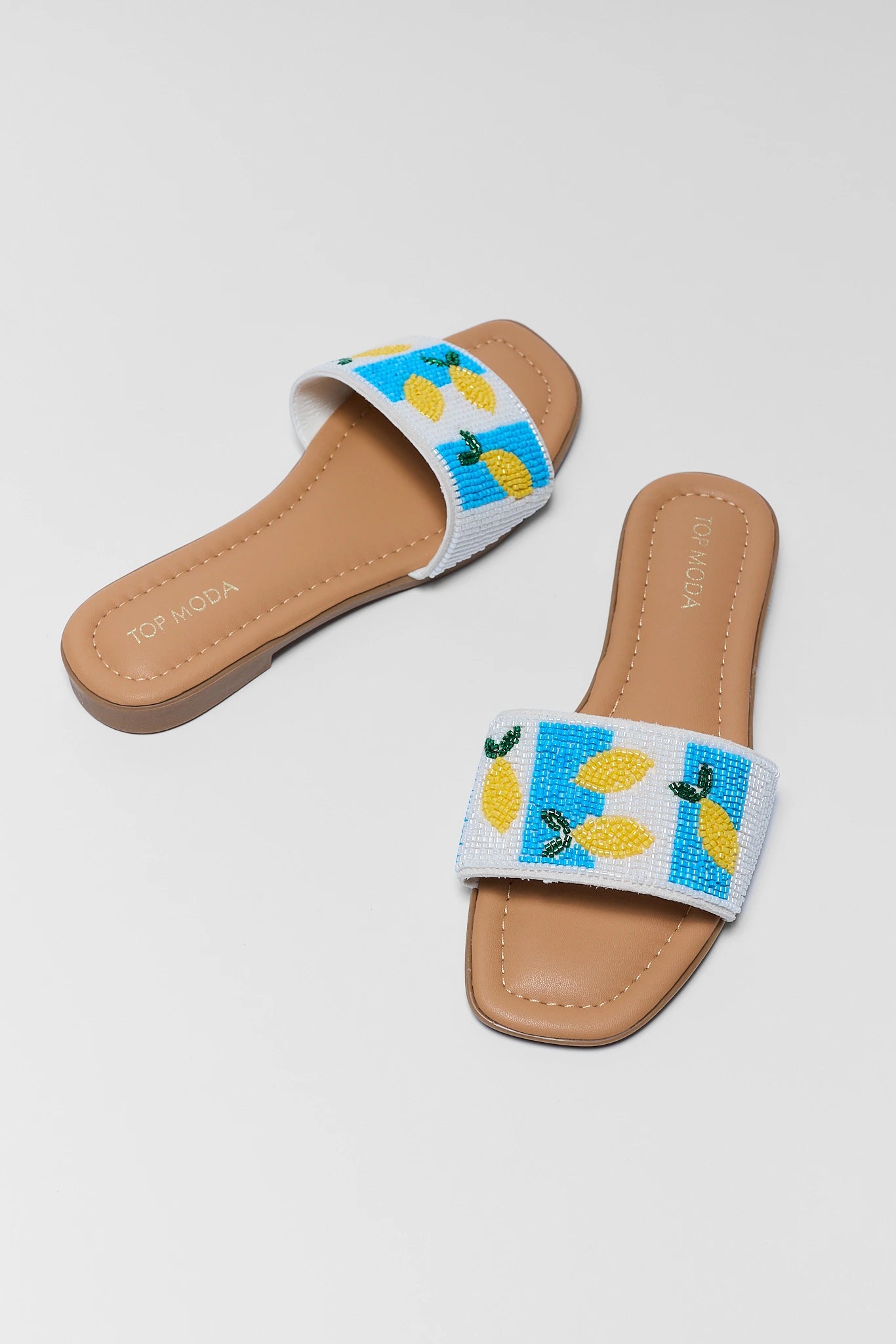 Pair of sandals with lemon design on a light gray background