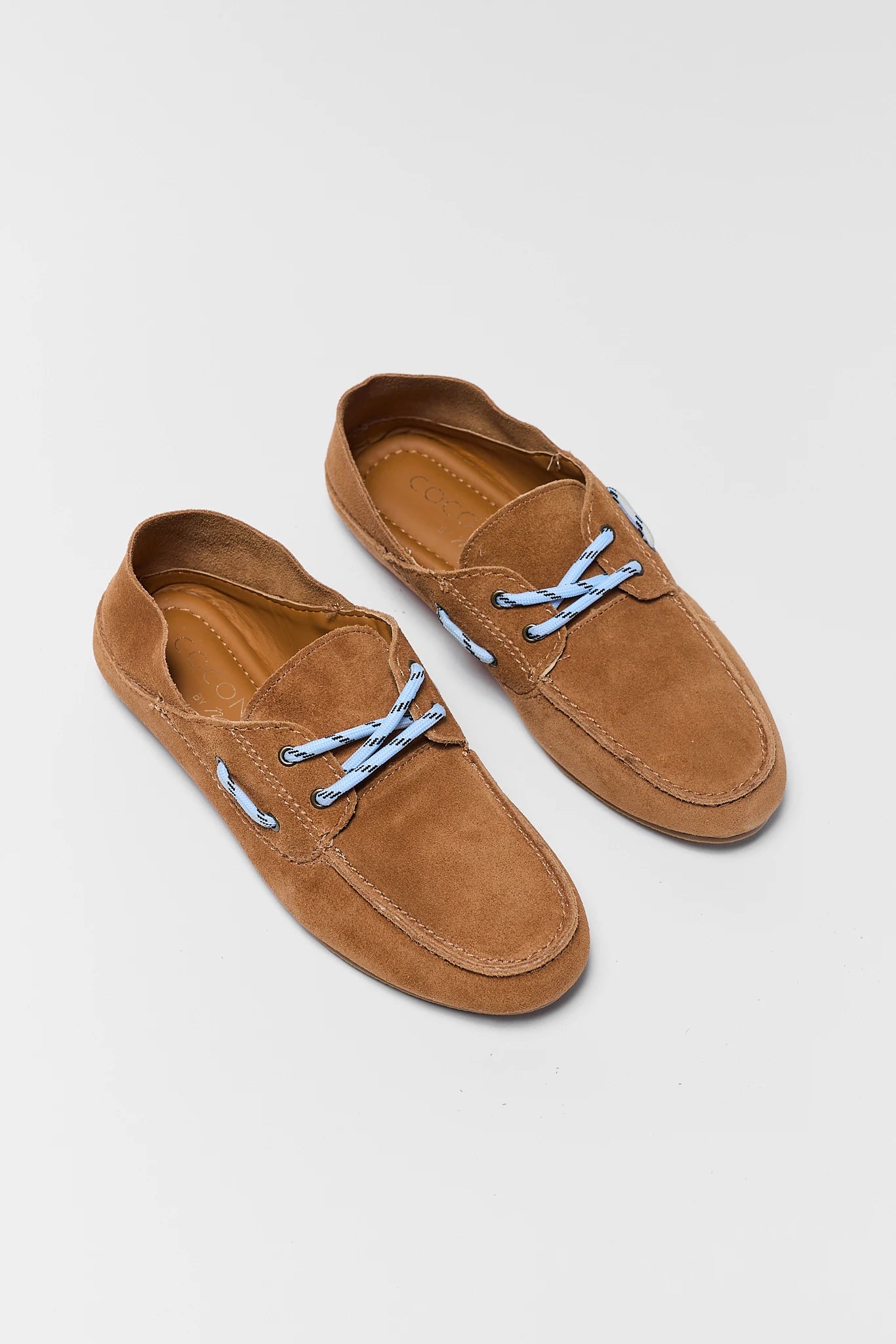 two Pair of brown suede loafers with blue laces on a light gray background