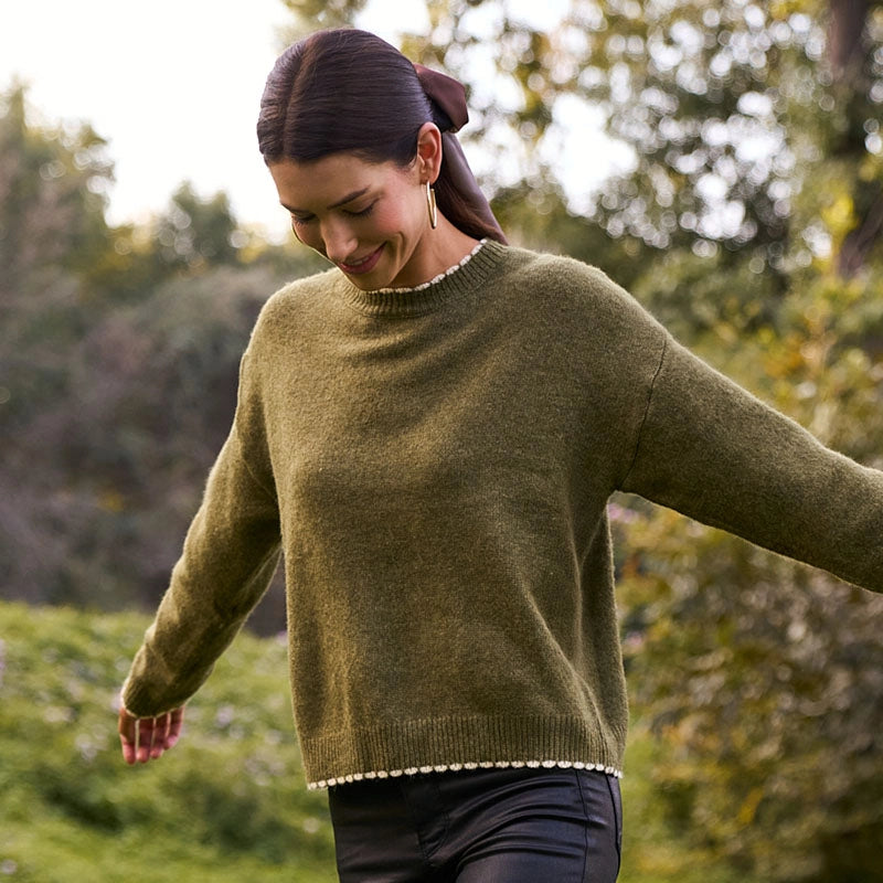 Woman wearing a green sweater with a blurred natural background