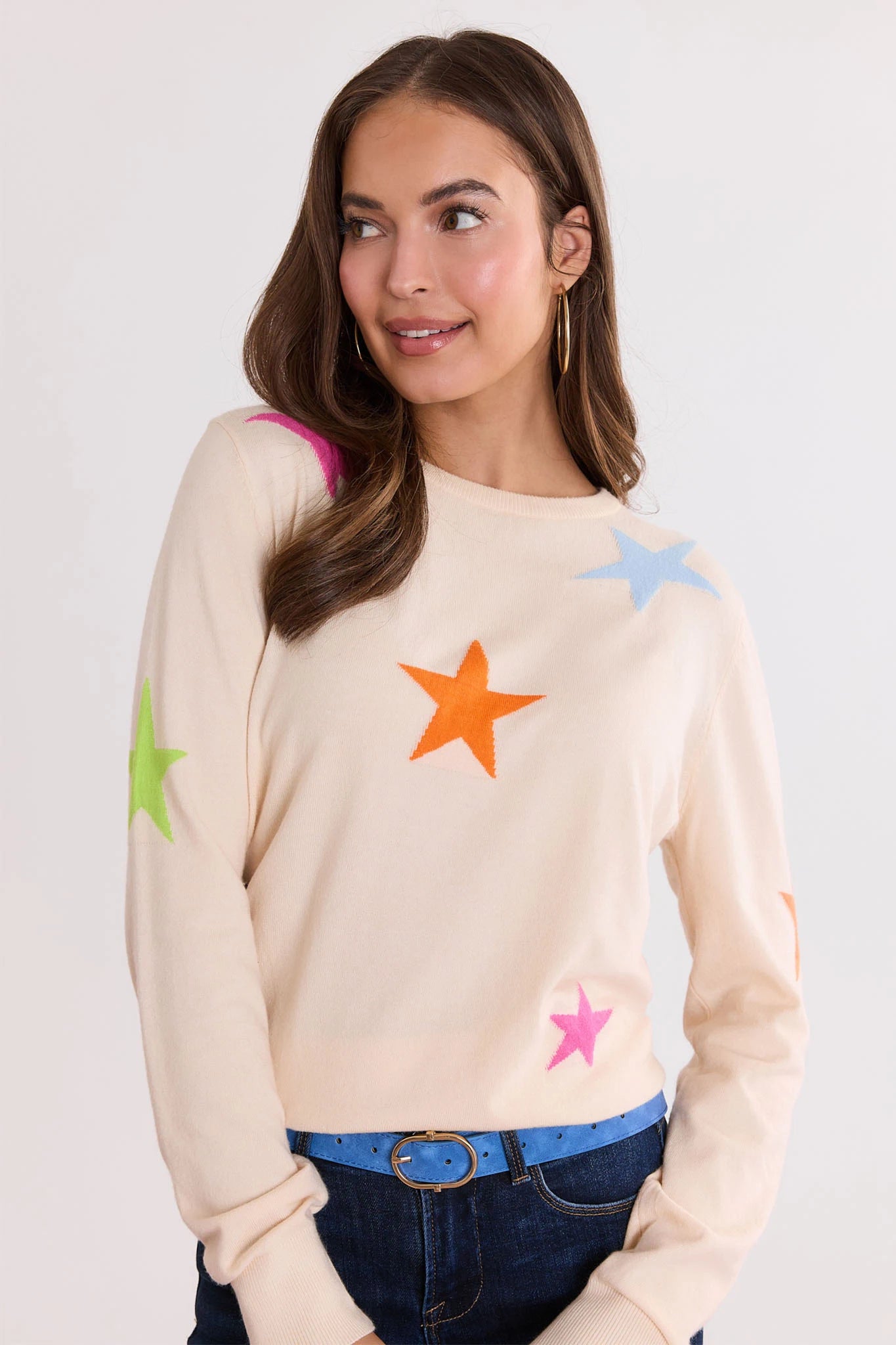 Woman wearing a Luna Cream Star Knit Sweater with colorful star patterns on a plain background