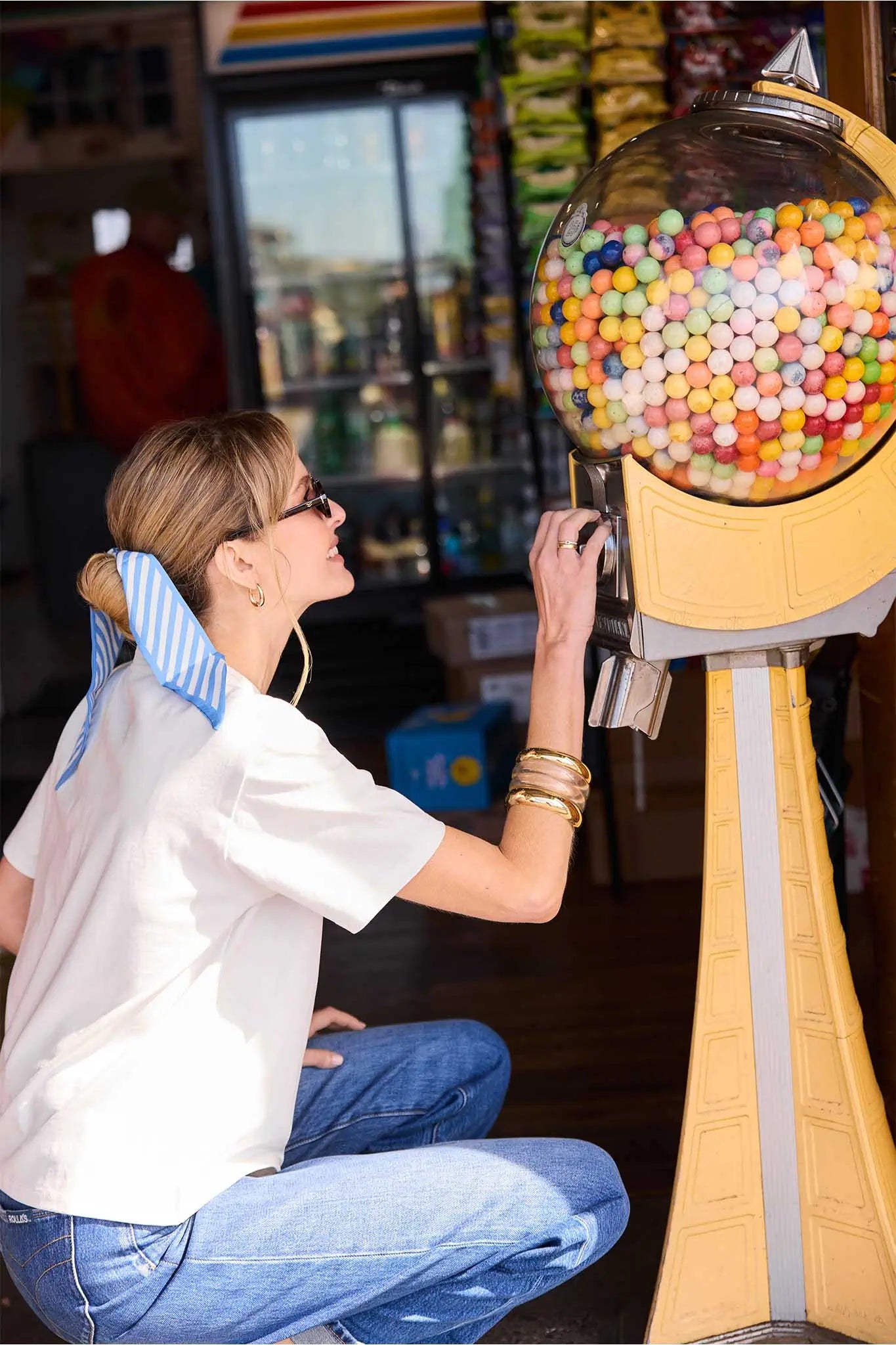 Person interacting with a vintage-style gumball machine filled with colorful gumballs.