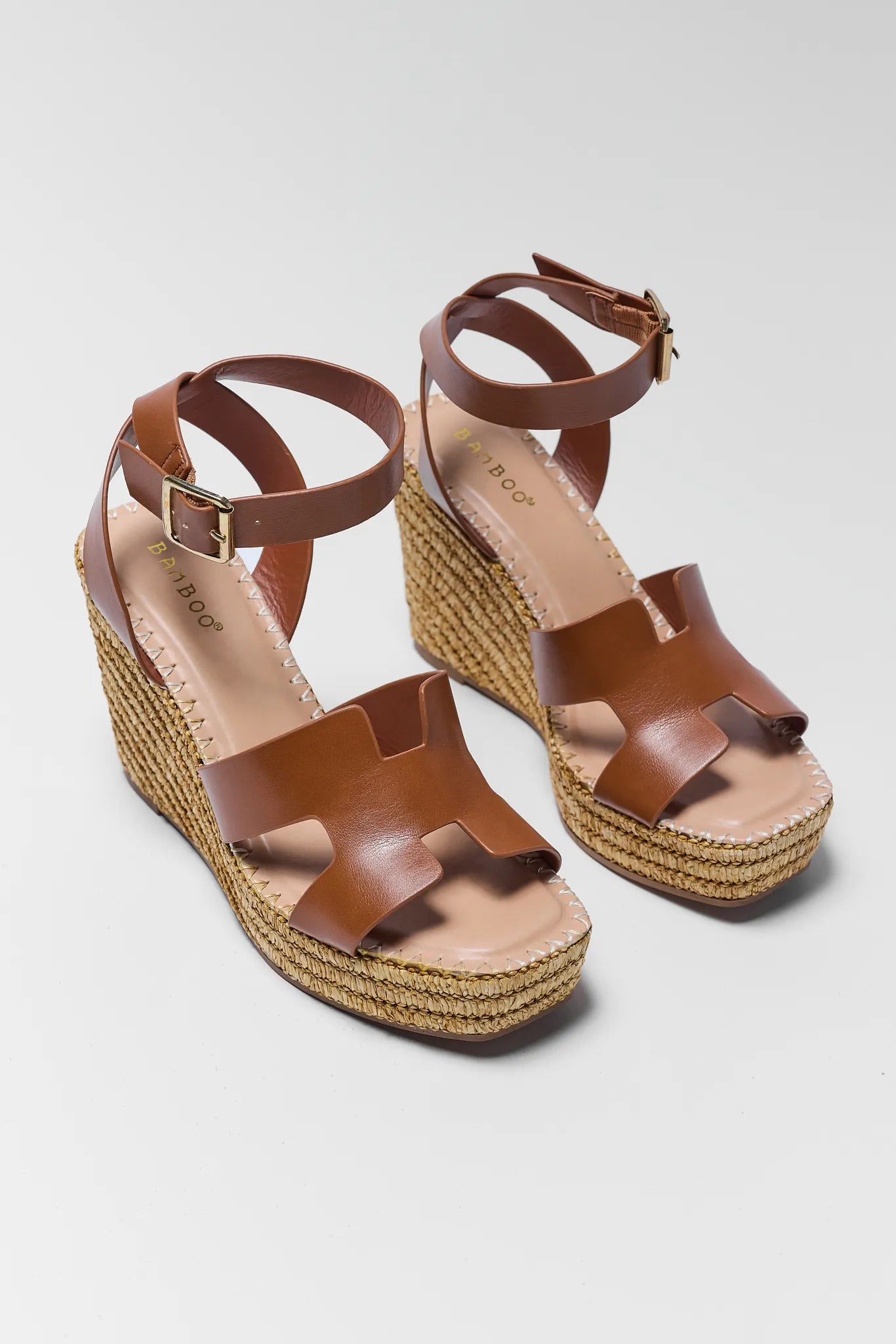 Brown wedge sandals with espadrille sole on a light gray background